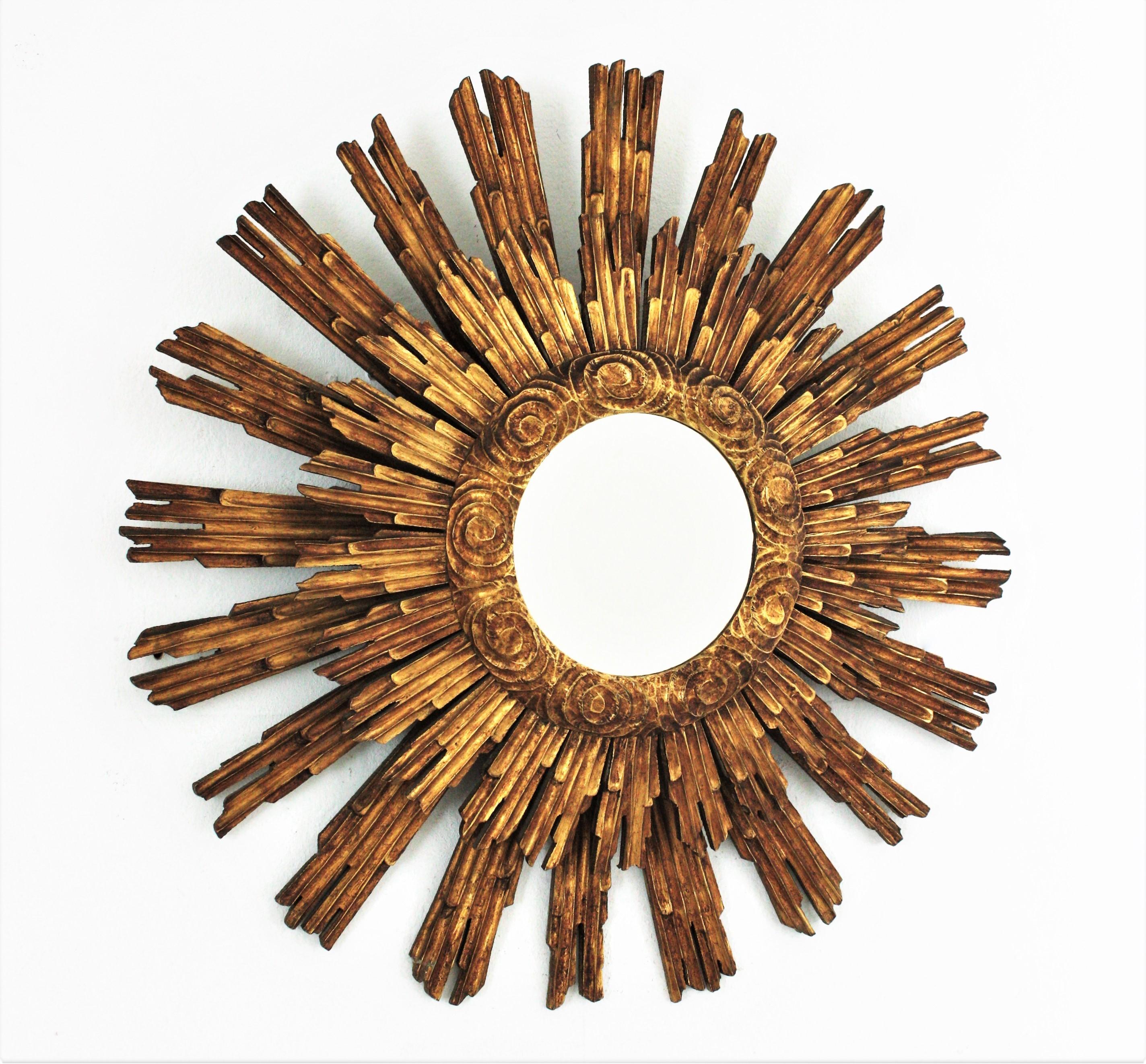 One of a Kind Hand Carved Double Layered Giltwood Sunburst Mirror. Spain, 1930s- 1940s.
This wall mirror features a carved giltwood frame made of a layer of long rays at the back part and a layer of shorter ones at the front part. The ring