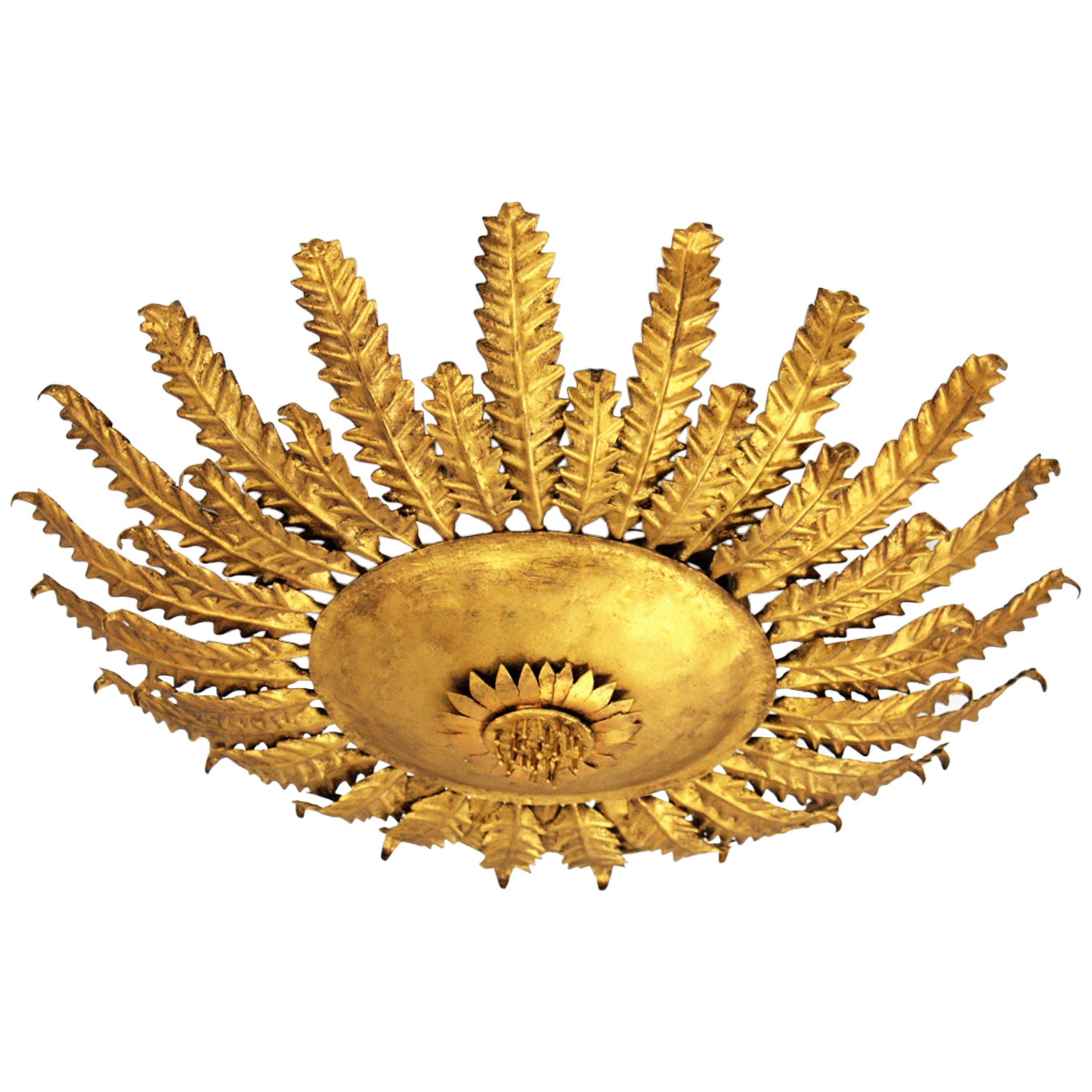 Gilt iron sunburst sunflower ceiling light fixture / wall sconce, Spain, 1950s
This eye-catching gilt iron flower burst wall light or ceiling fixture features scalloped leaves in two sizes surrounding a central sphere adorned by a sunflower