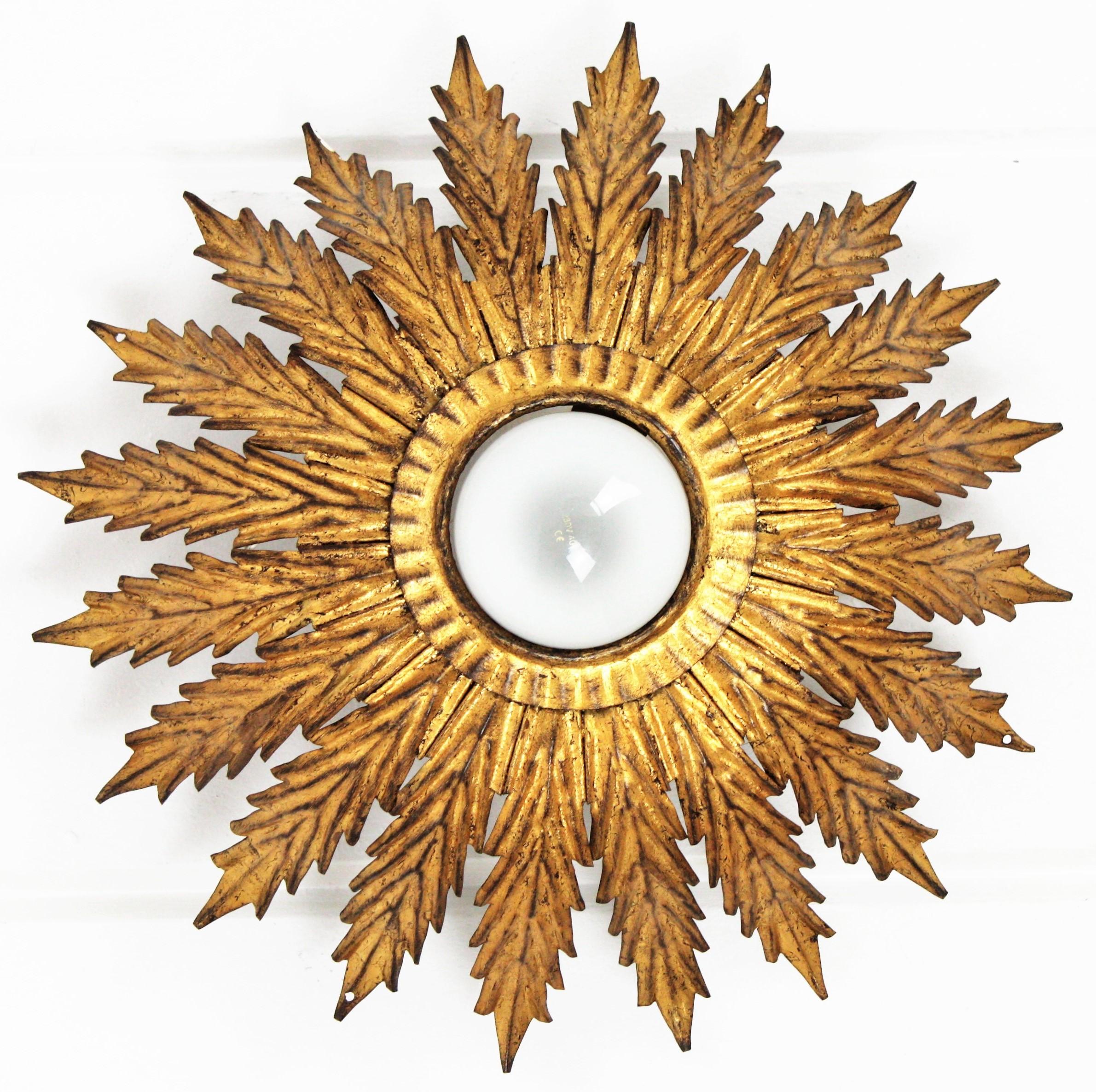 Elegant Hollywood Regency hand-hammered gilt iron sunburst flower light fixture / flush mount, France, 1940s-1950s.
This flush mount ceiling light features a wrought iron structure comprised by gold gilt iron scalloped leaves. The part surrounding