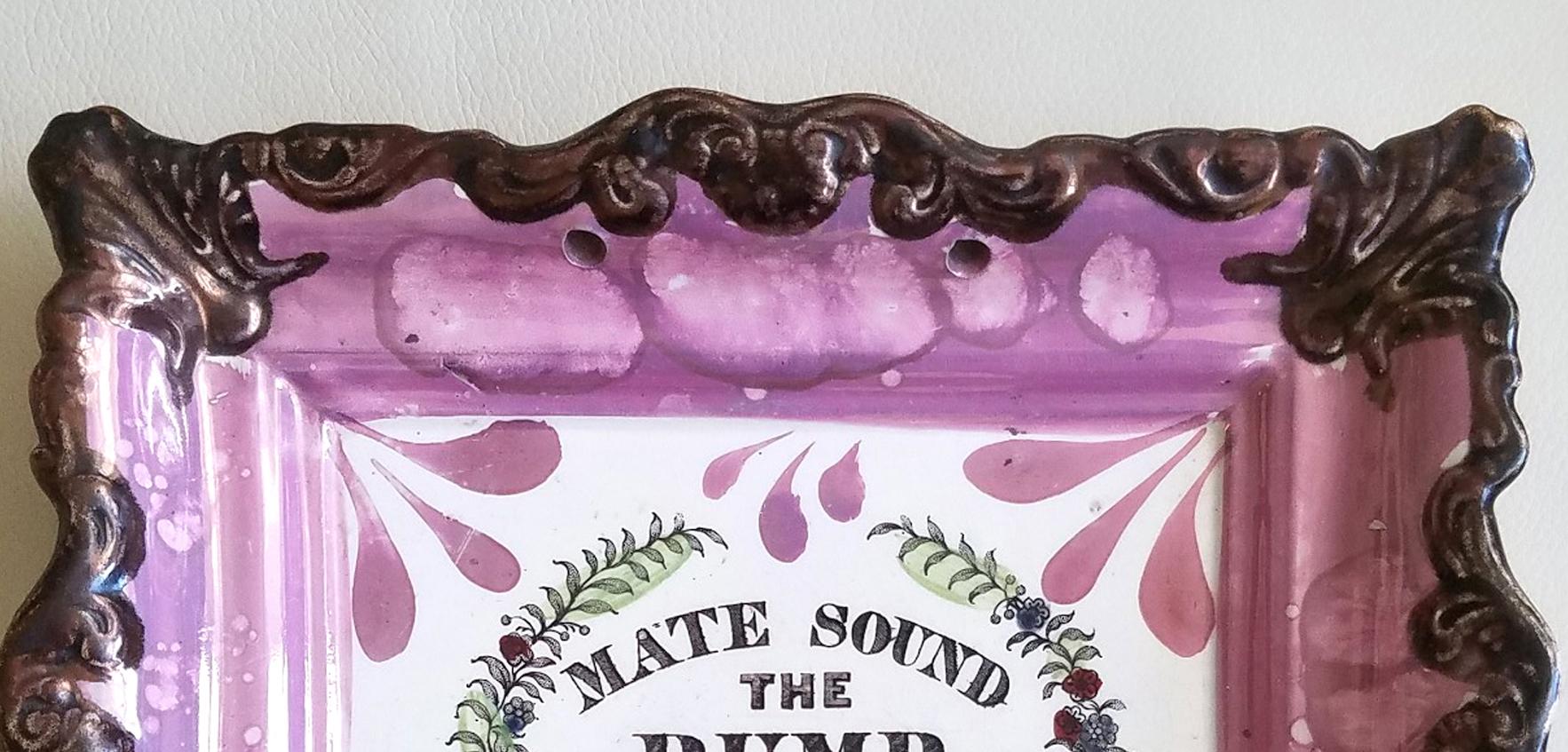 Sunderland Lustre Marine Plaque, 
Mate Sound the Pump, Morning Noon & Night, 
Dixon & Co., 
Circa 1820-1840.

A rectangular moulded pink lustre plaque with a painted motto in the centre within a laurel leaf surround.

According to J. Welles