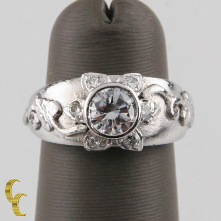 Gorgeous Platinum Band ring with GIA-Certified Bezel-Set Round Brilliant Center Stone
Features Sunflower Design with Center Stone Head and six diamond accent stone petals, with bas relief vine detailing
Ring Size = 4.5
Width of Band at Front = 8.5