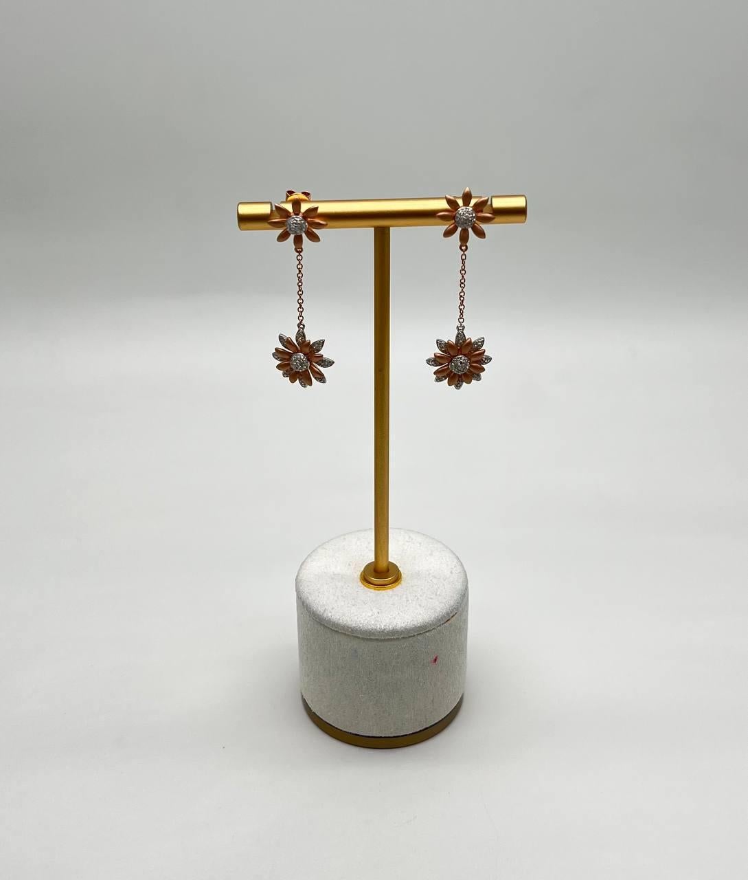 Scopri l'eleganza di questi orecchini a goccia floreali. Caratterizzati da intricati motivi floreali, ogni orecchino è impreziosito da un diamante centrale scintillante circondato da delicati petali. Il design è completato da una graziosa catena che