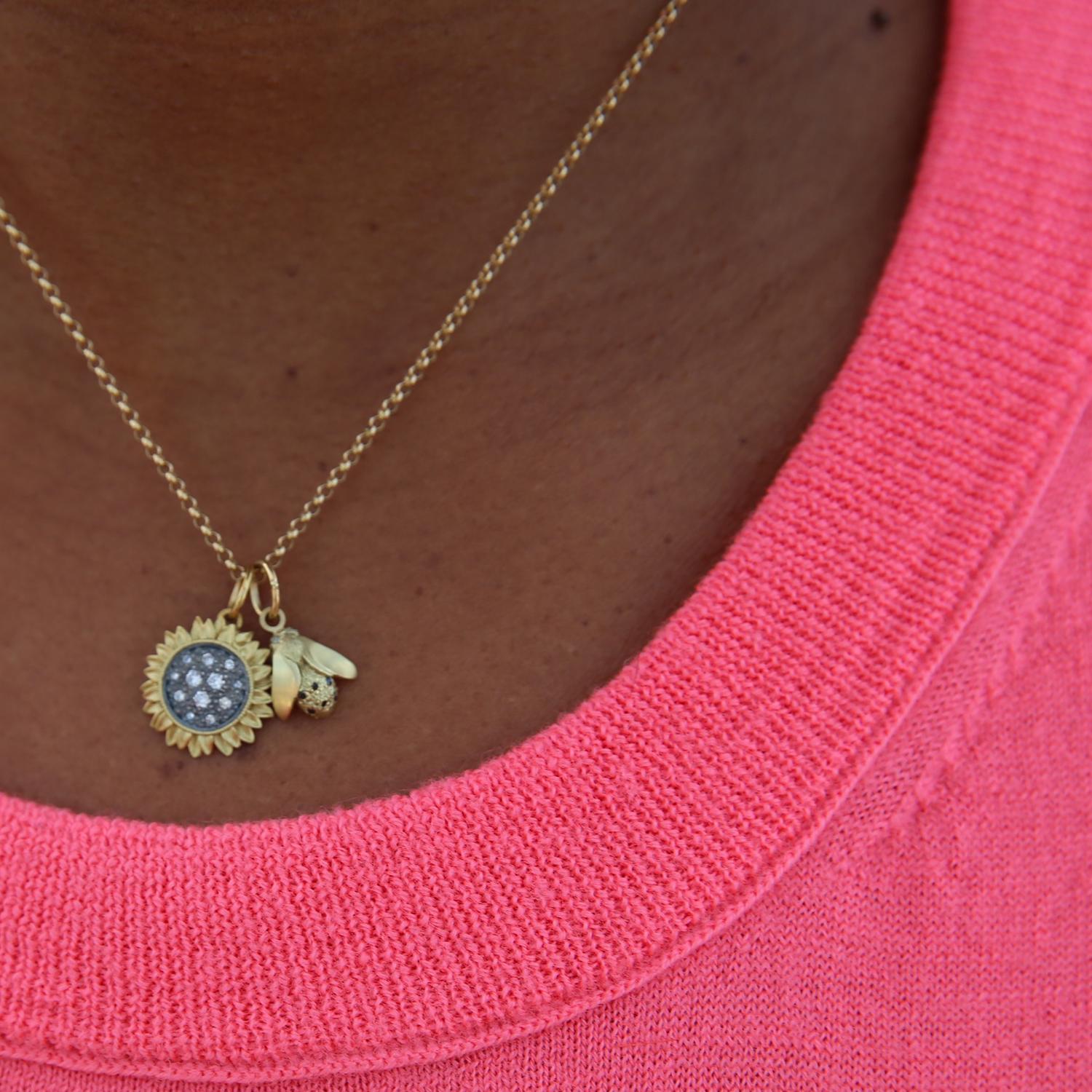These sparkly sunflowers are even more eye-catching than the real thing!
Our sunflower pendant has 18k yellow gold petals surrounding diamonds pave set in oxidized sterling silver. The delicate flower hangs from a 16-inch 14k yellow gold chain. 