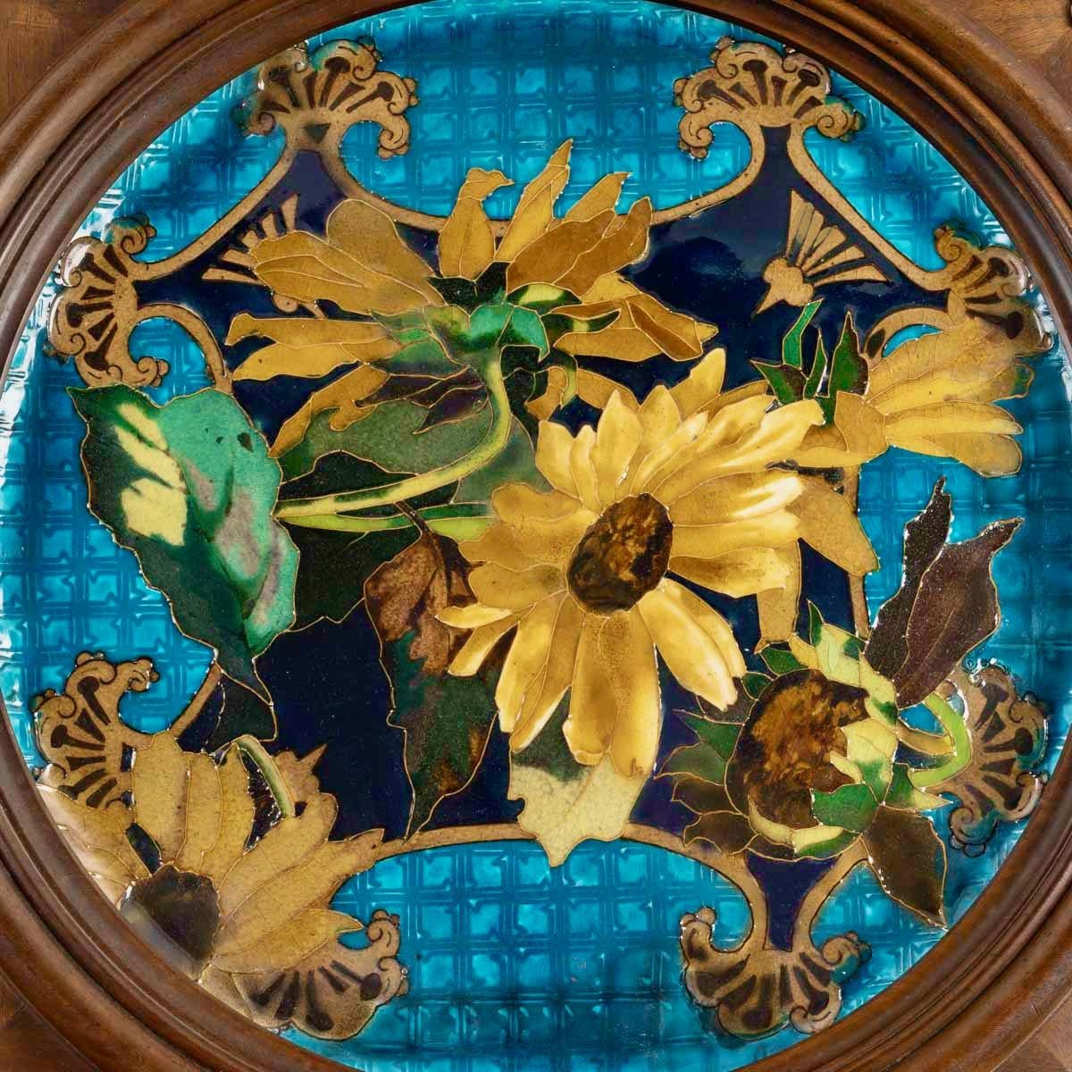 “Sunflowers”
A 19th Century Polychromed Faïence Charger designed with bulging and beaming Sunflowers 
On a “Blue Deck” background simulating a trellis
In its original wooden frame decorated with chiseled brass spandrels 
Aesthetic Movement
Circa