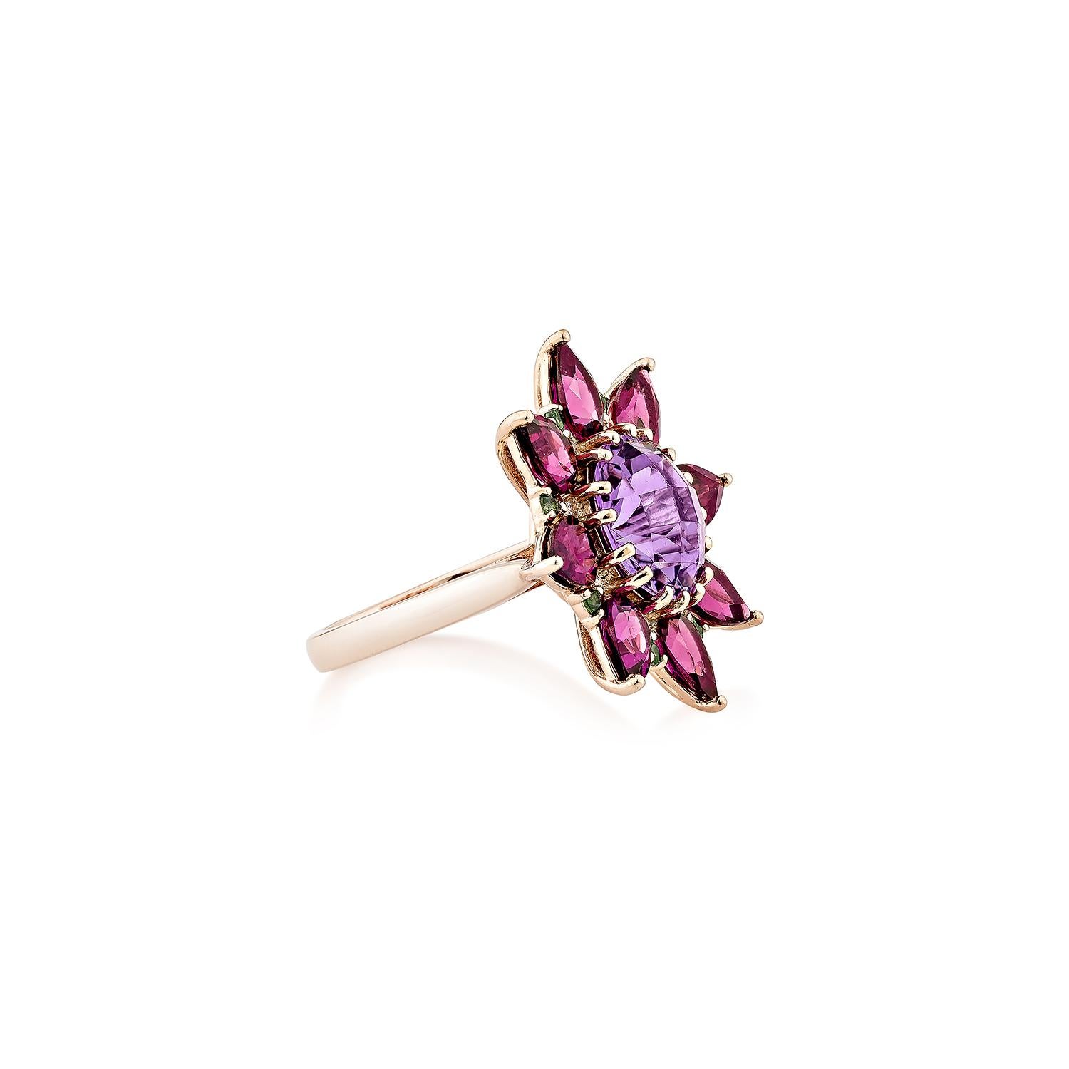 A statement floral ring featuring a captivating oval-cut amethyst at the center, surrounded by a halo of pear-shaped rhodolites arranged in a sunflower motif. Accentuated with sparkling diamonds and vibrant tsavorites, all set in 14K rose gold for a