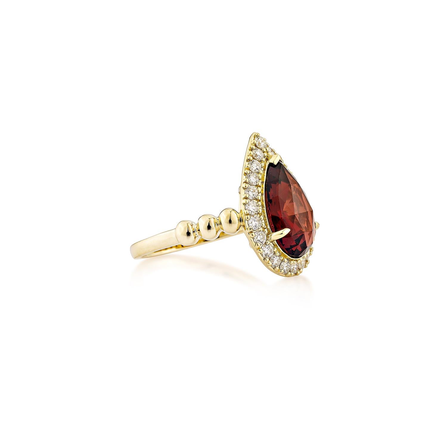 A striking Red Garnet Fancy Ring in 14K Yellow Gold, featuring a pear-shaped garnet gemstone embraced by a sparkling halo of diamonds. The elegantly sculpted gold band adds a touch of refinement, making this piece a timeless statement of