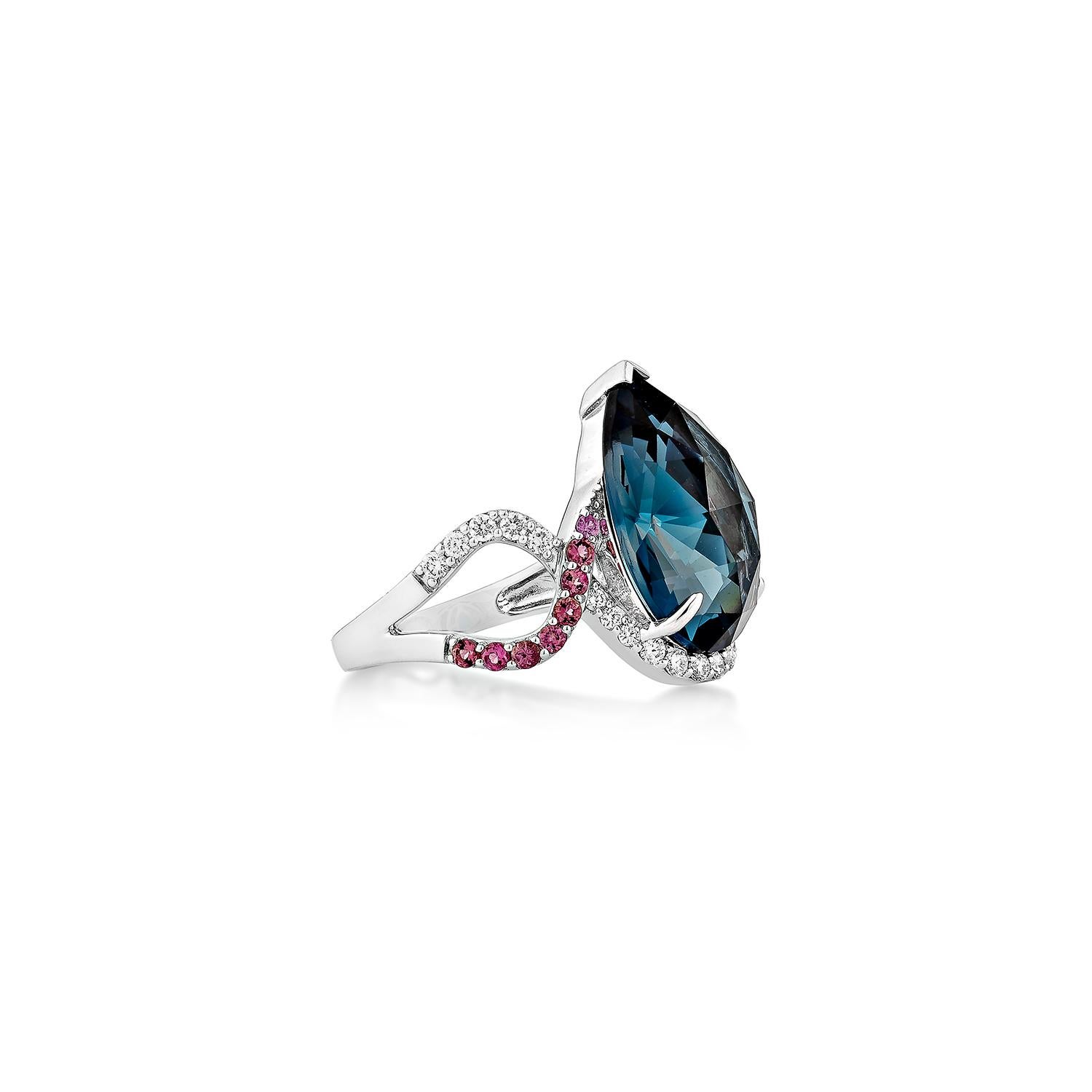 Uno splendido anello con topazio blu di Londra a forma di pera incastonato in oro bianco 18 carati, impreziosito da diamanti scintillanti e da una delicata tormalina rosa. Il design intrecciato aggiunge un tocco di eleganza e di modernità, rendendo