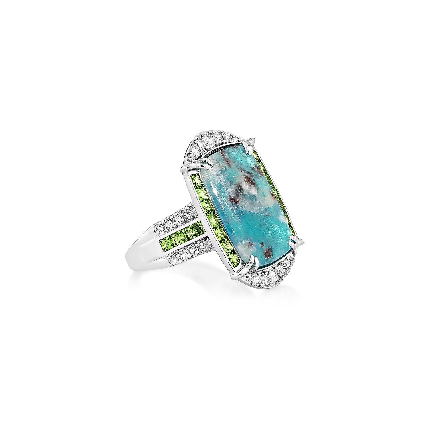 Llamativo y sofisticado, este audaz anillo de cóctel presenta una fascinante gema Paraiba de talla cojín acentuada con vibrantes tsavoritas verdes y un reluciente borde de diamantes blancos, todo ello engastado en oro blanco de 18 quilates. Una
