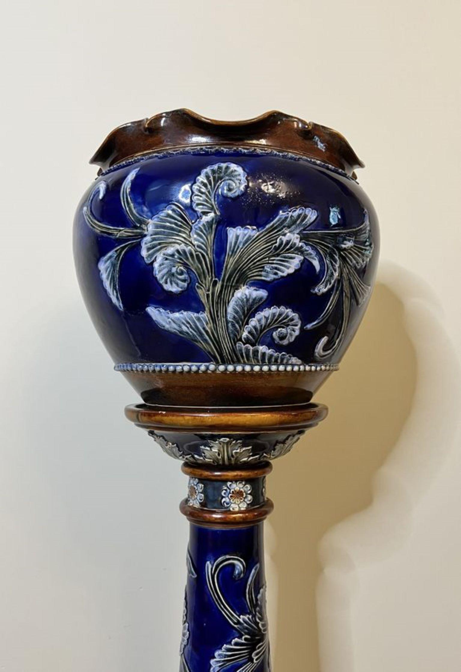 Sunning quality antique Royal Doulton jardiniere on a stand having a quality jardiniere with a wavy shaped top with a blue ground decorated with flowers and leaves in lovely blue and green colours, on the original pedestal standing on a circular