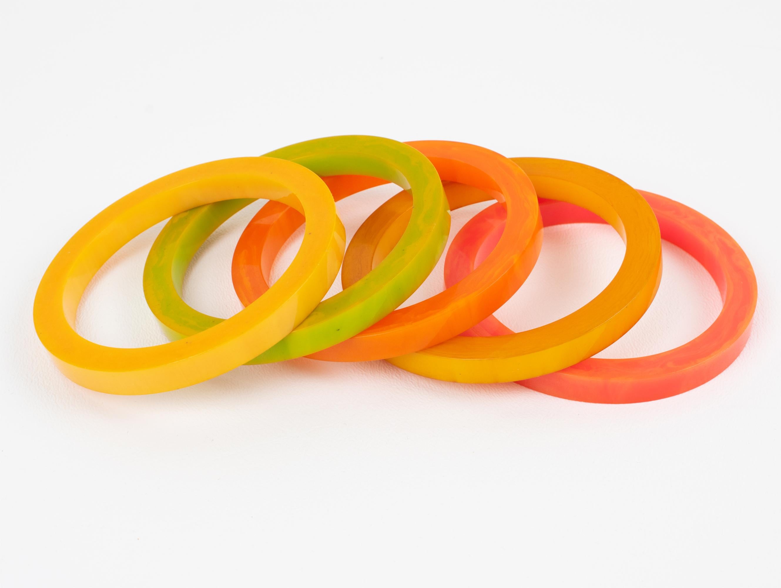 This easy-to-wear set of five Bakelite bracelet bangles features a chunky spacer-sliced shape. The bright, sunny colors—green pepper cheese marble, pink tequila sunrise marble, orange mango marble, yellow lemon drop marble, and curry orange—are