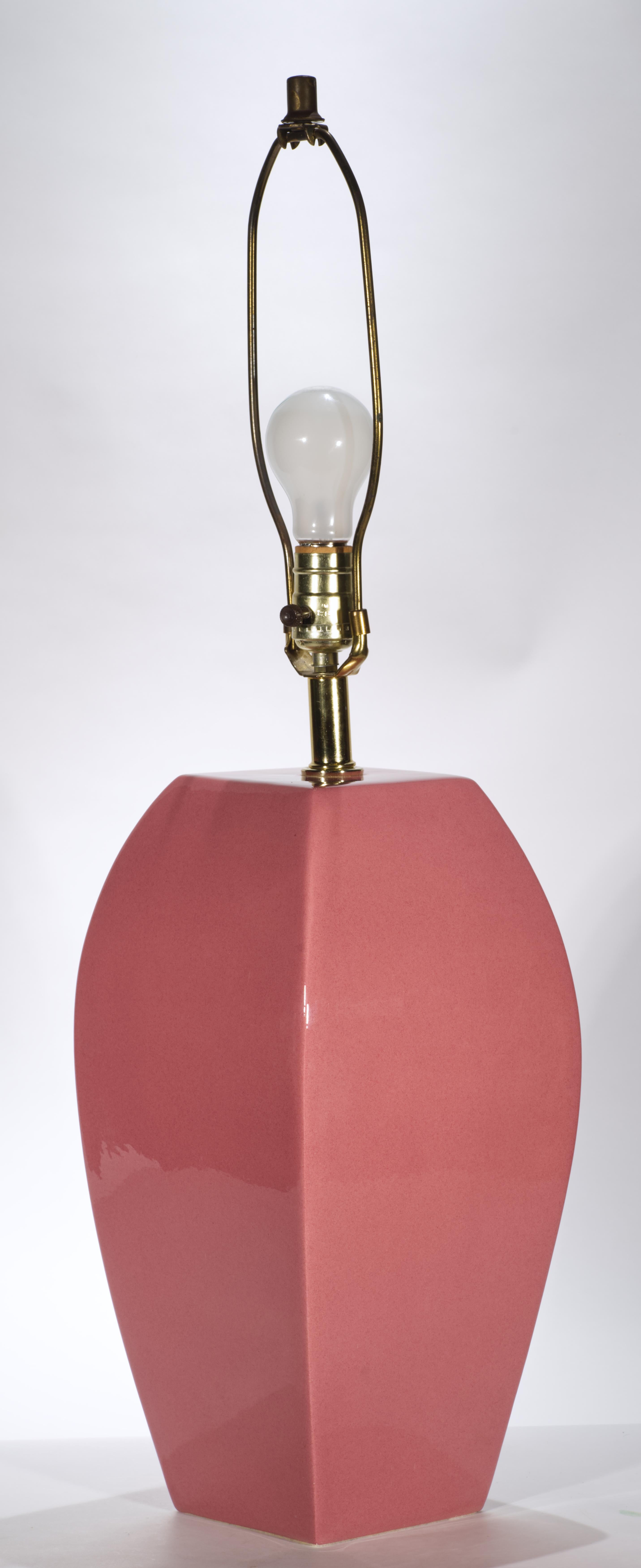  La lampada di design vintage in ceramica artistica presenta un corpo astratto e sovradimensionato a forma di urna, decorato con smalto lucido monocromatico. Il complesso colore rosa dello smalto aggiunge carattere e presenza alla lampada in