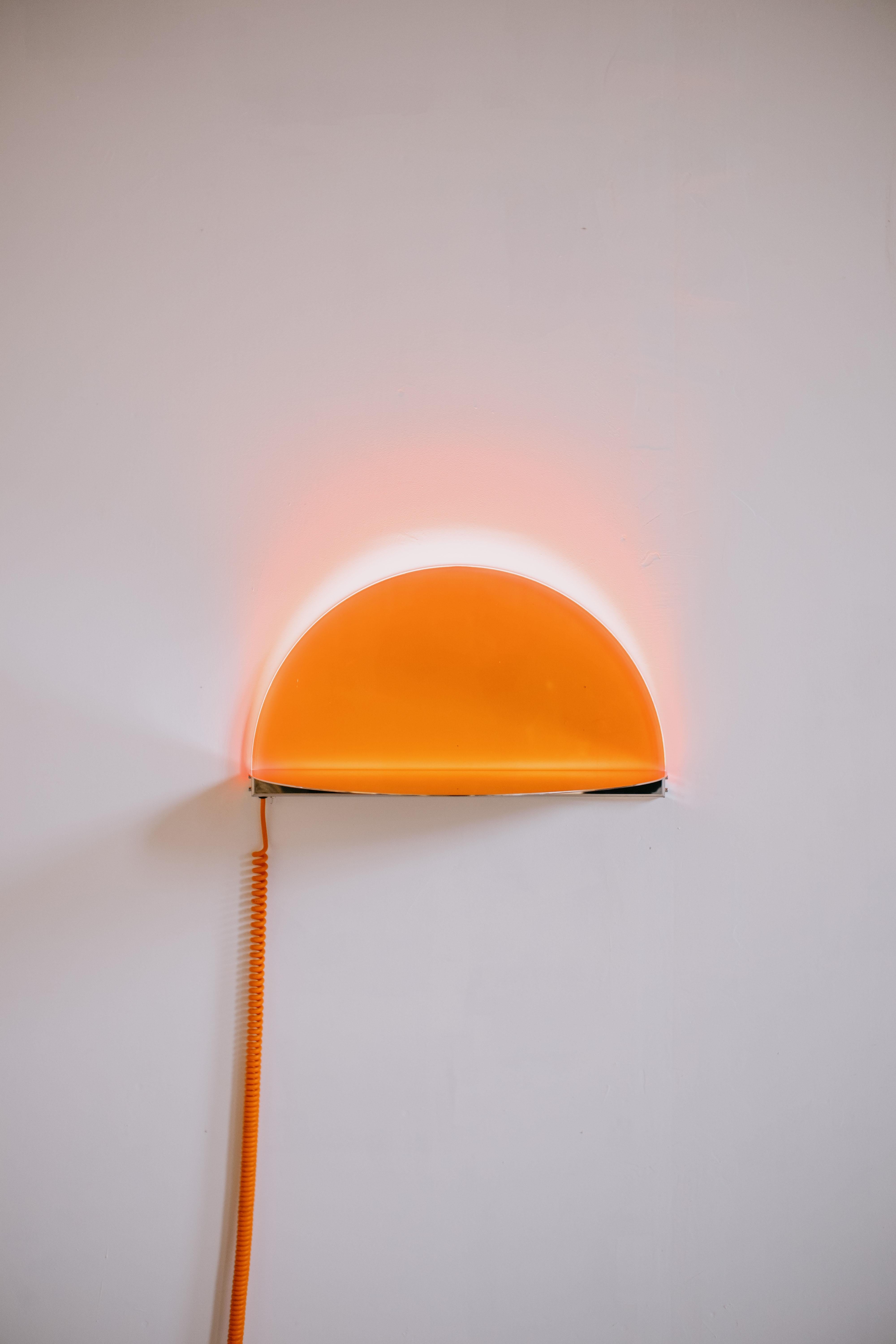 Sunset Wall Light by Amber Dewaele
Dimensions: D 62 x W 32 x H 34 cm.
Materials: Acrylic and polished stainless steel.

Sunset Wall Light
The sunset wall light is inspired by that one beautiful summer evening when the sun sets in the sea. It is
