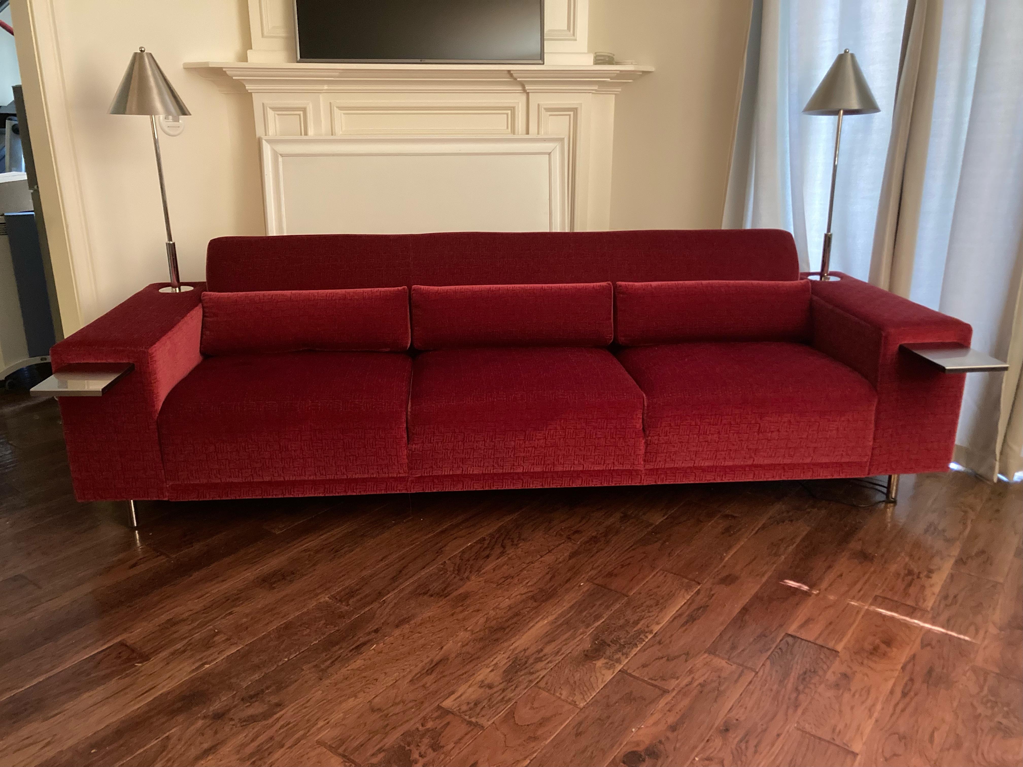 Sofa is part of Brueton’s “America” seating, a collection featuring brushed stainless reading lamps, pull out trays and 3 removable kidney pillows. 
Lamps are stainless steel with a satin finish. Upholstery is a soft mohair like raspberry.
Arm