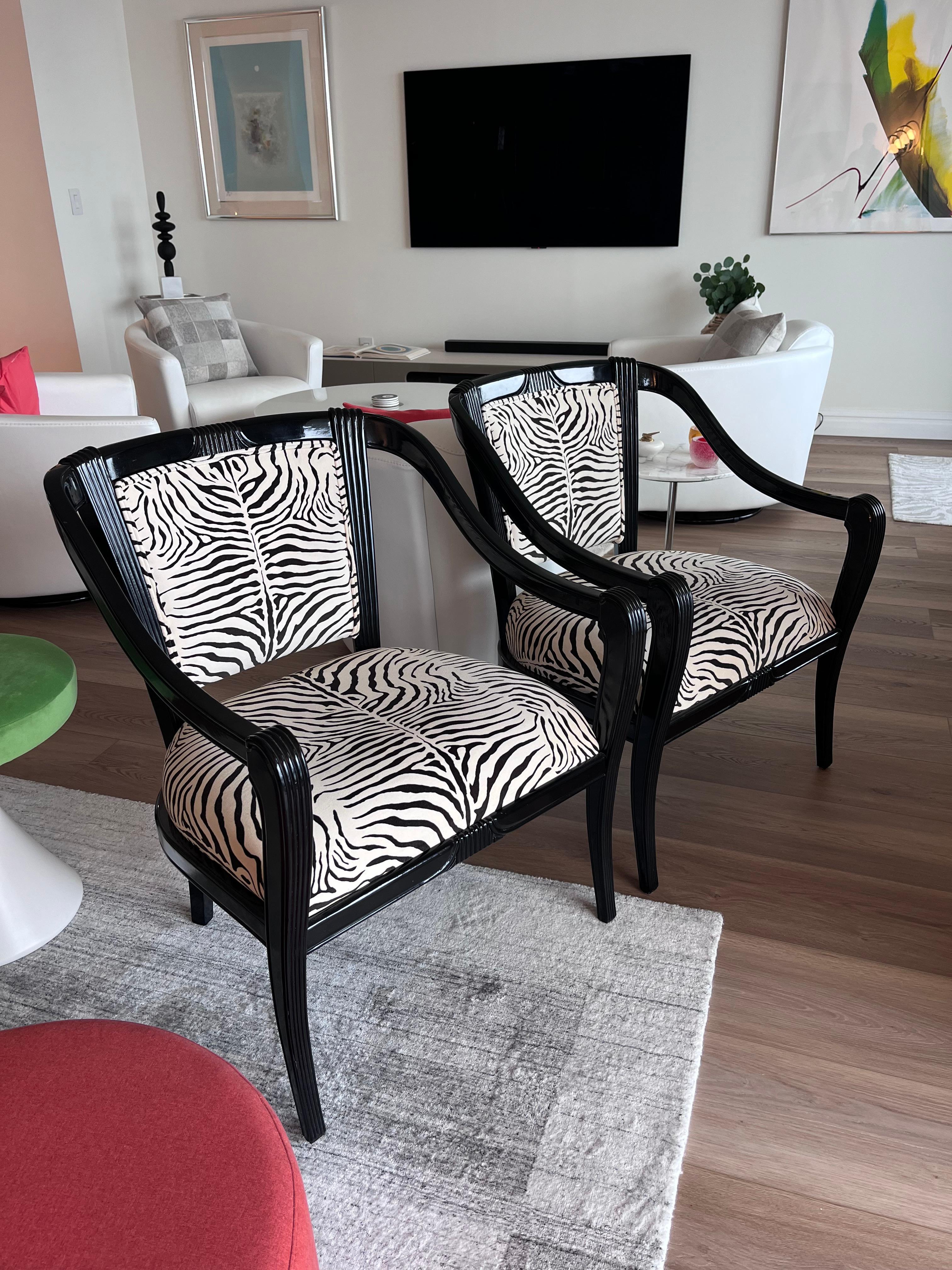 Coppia sofisticata e super chic di poltrone imbottite in velluto di cotone zebrato con struttura in legno semilucido nero con eleganti dettagli scanalati.  La tappezzeria zebrata è color crema e nero scuro.  Il doppio guardolo è un tocco di