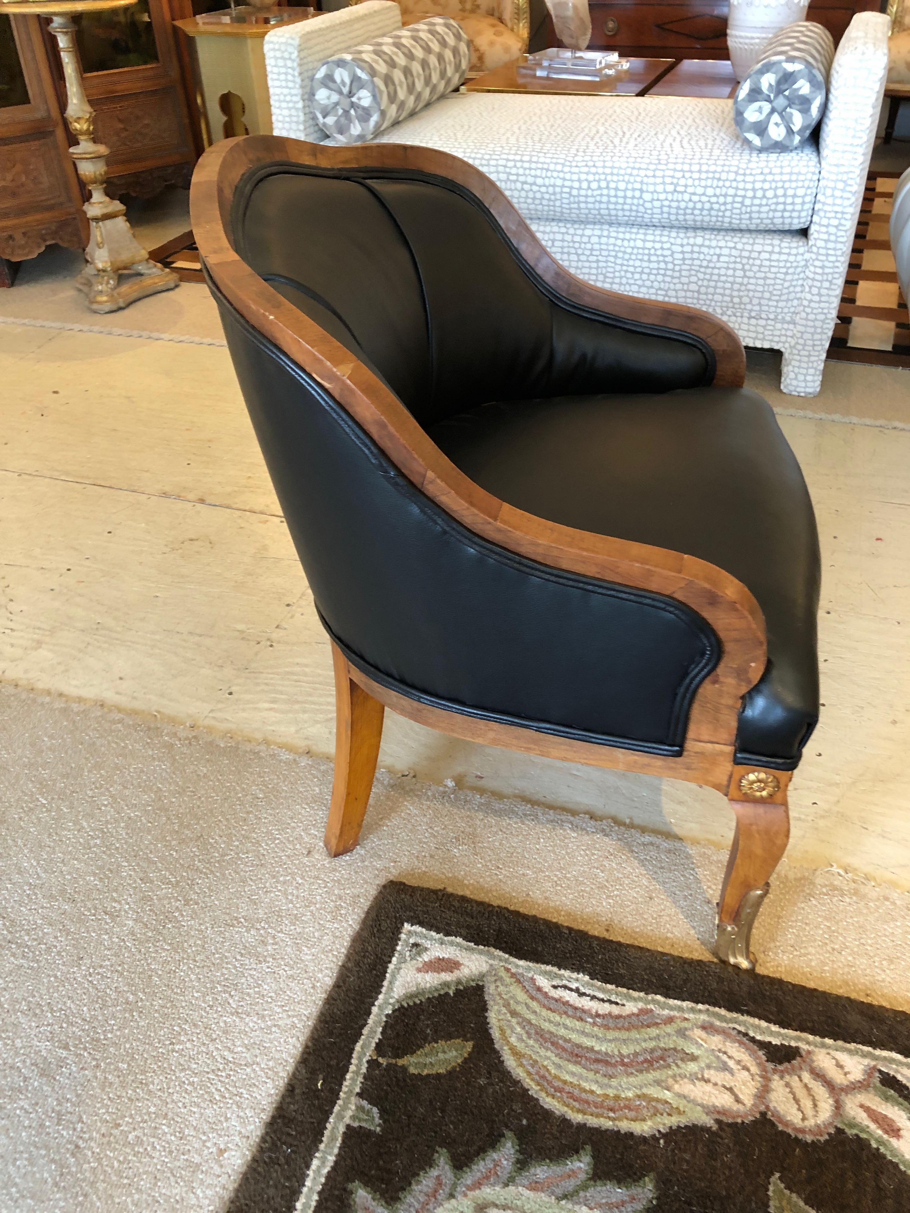 A fabulous club or library chair, compact with a curved back and cabriole legs, having handsome bronze rosettes and caps on the feet. Recently updated and made more handsome with faux leather black upholstery that passes for the real thing.