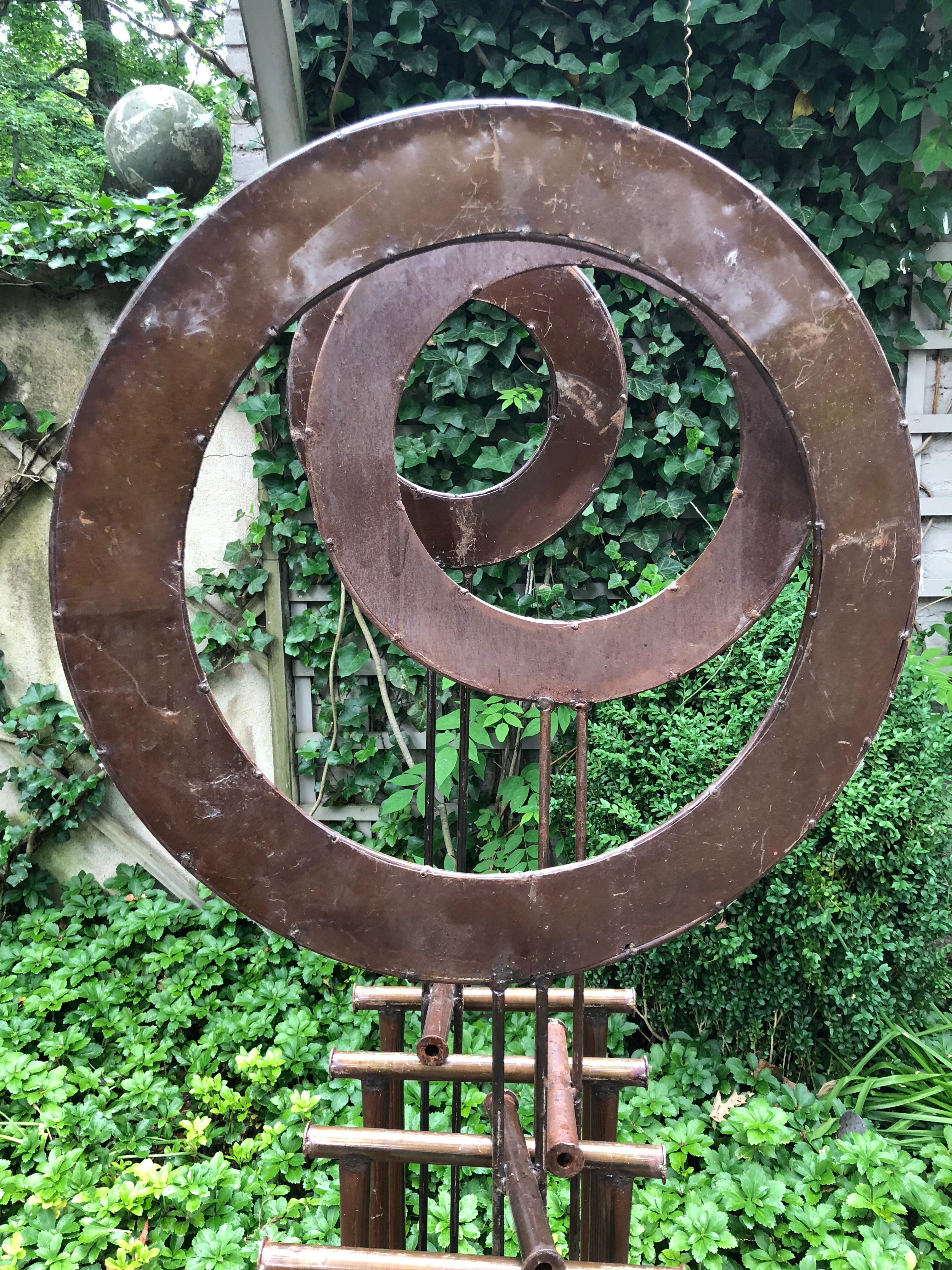 Super cool Kinetic sculpture in wrought iron and metal. The sculpture has 3 circles on rods that rest on a metal base. The upper circles measure 25 inches 17 and 13 in diameter. This piece makes a wonderful addition to any landscape.
 