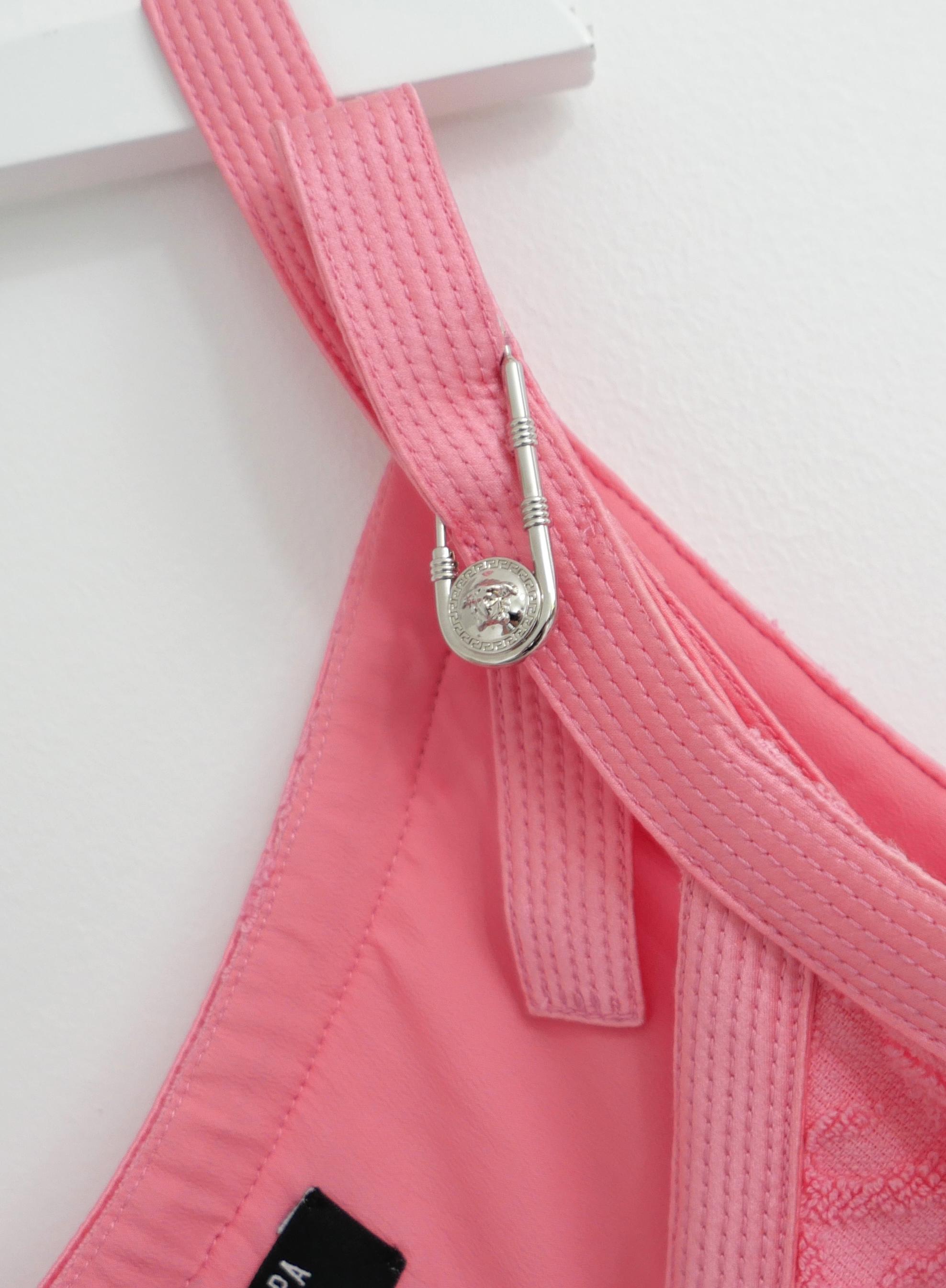 Top crop con logo Versace x Dua Lipa in spugna di cotone. Comprato per £825 e non indossato. Realizzato in spugna di cotone rosa corallo con un'ampia copertura.  Logo Versace, orlo con frange, bordi in raso cuciti e finiture con spille da balia a