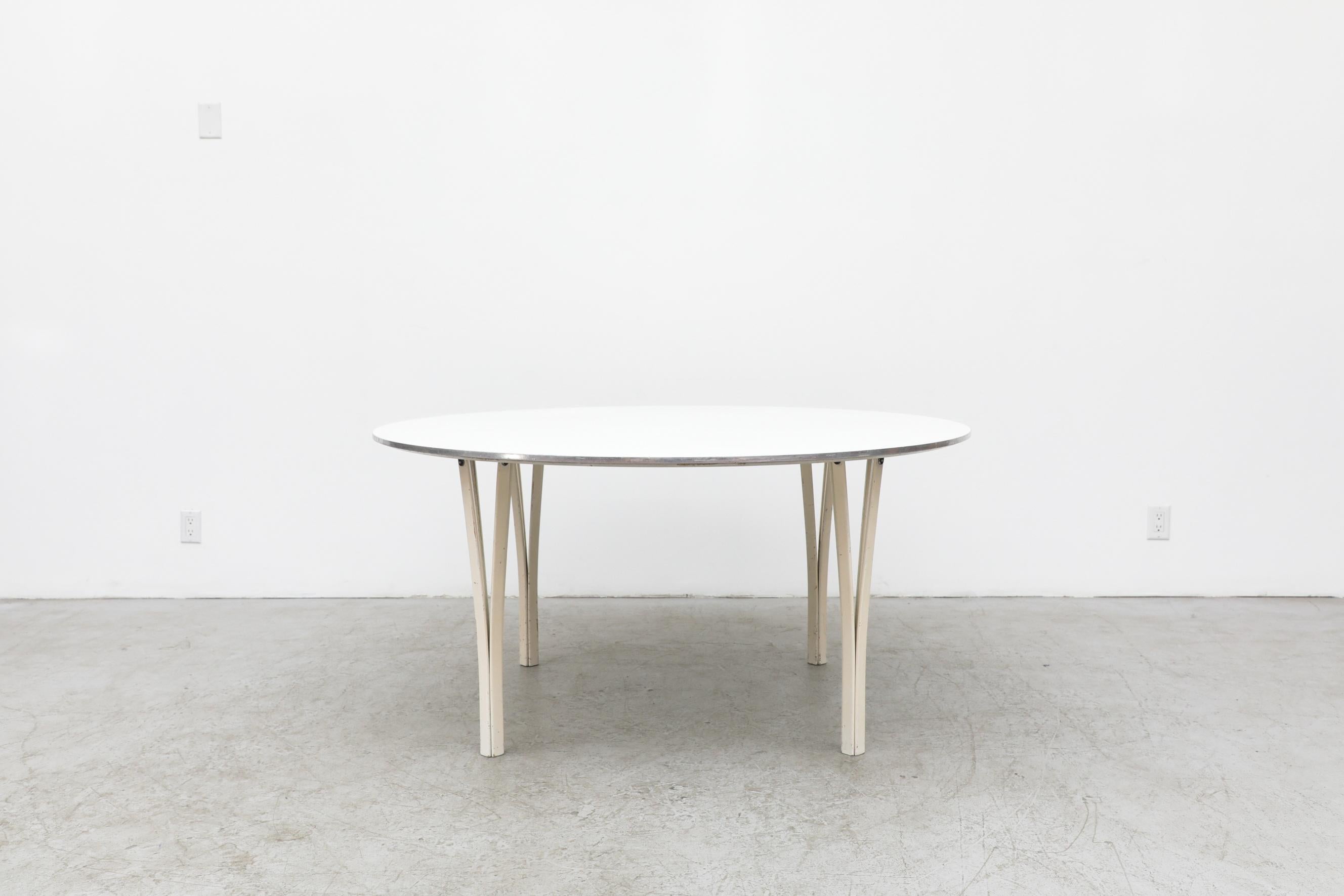 Super Ellipse round dining or center table by Piet Hein & Bruno Mathsson for Fritz Hansen. In original condition with visible scuffing to the lacquer on the legs as well as visible wear to the metal edge banding. Wear is consistent with its age and