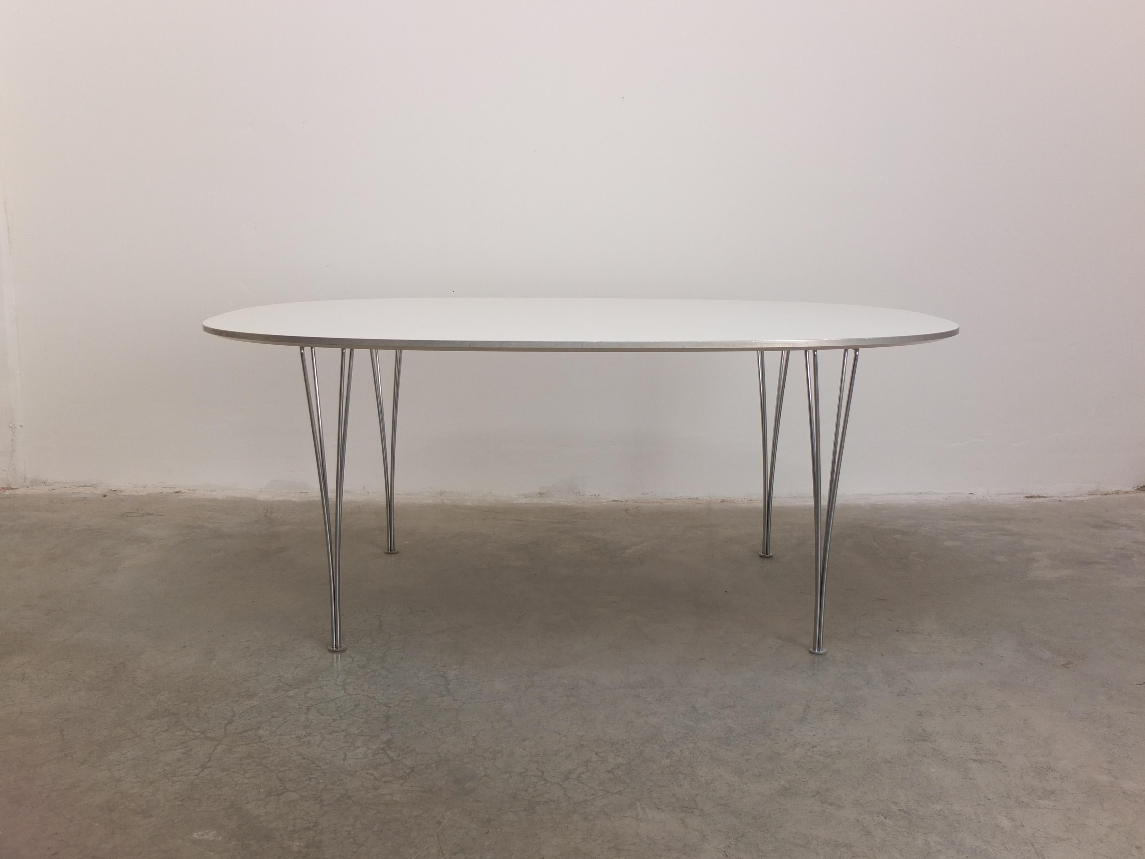 A ‘Super-Elliptical’ dining table designed by Piet Hein & Bruno Mathsson in 1968. This example features a white laminated top with an aluminum edge, combined with the signature chromed steel spanlegs. Produced by Fritz Hansen in 2005 (labeled). This