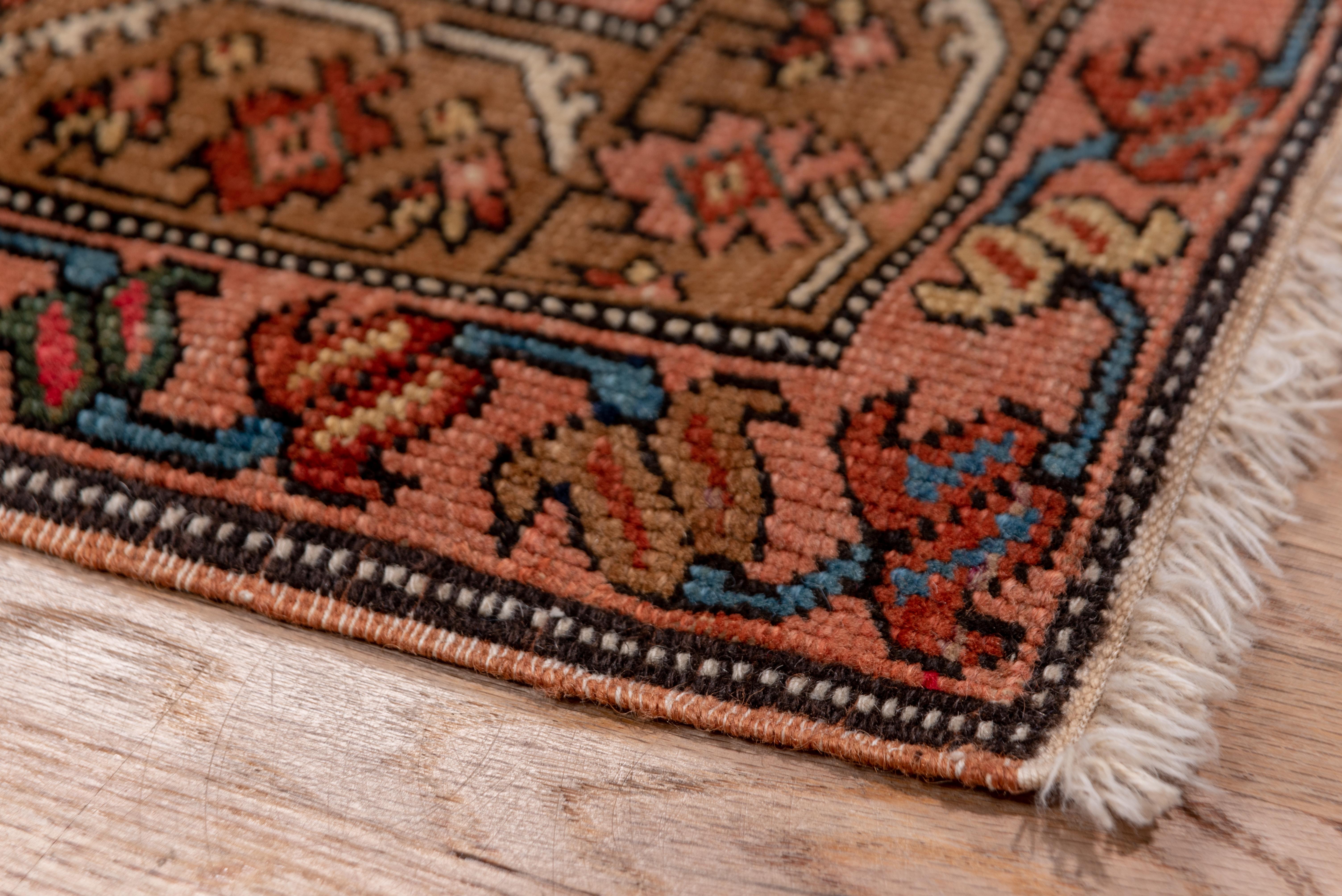 The dark royal blue natural open field is centered by a full-width pole medallion of five red lobed elliptical medallions, with smaller fitted hexagons and blunt arrowhead finials. Green minors with flip-flop meanders and central camel stripe with a