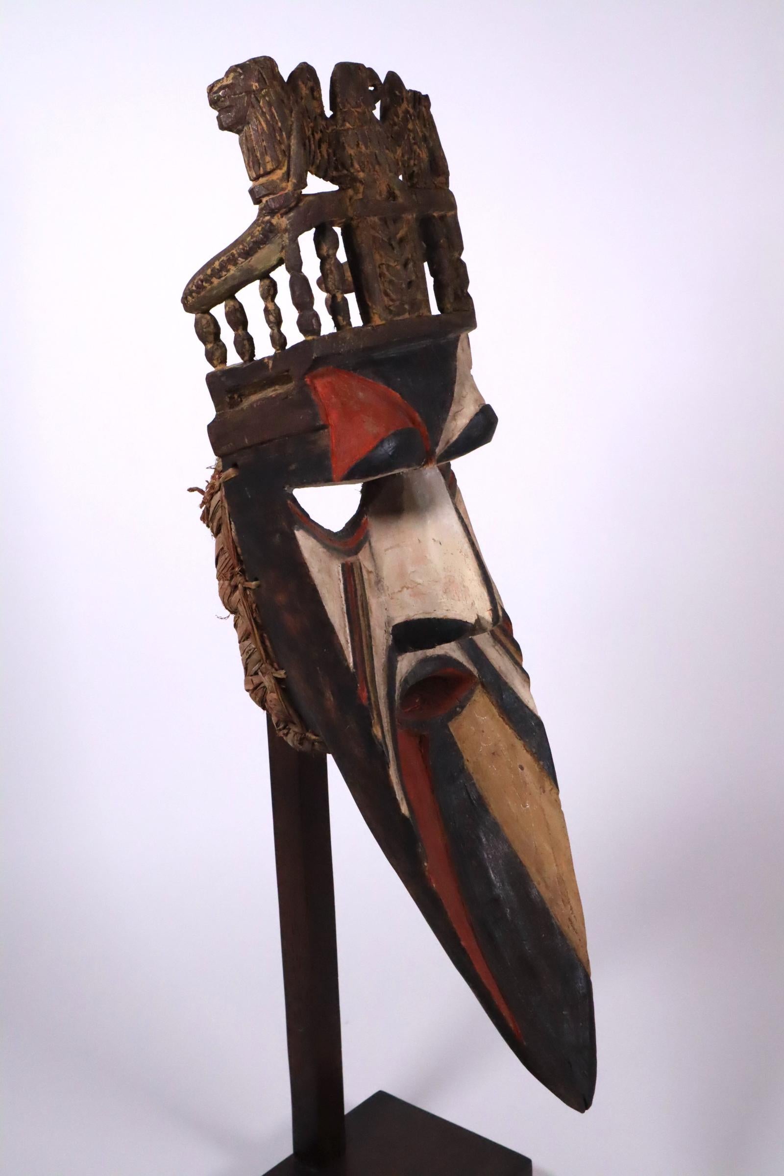 A superb and rare type of Igbo/Afikpo Theater mask, Nigeria, early to mid-20th century. Painted wood with fiber trim around back.
This mask is unique as it has a European style throne as a crown. The throne has curved arms, lobed posts, and a large