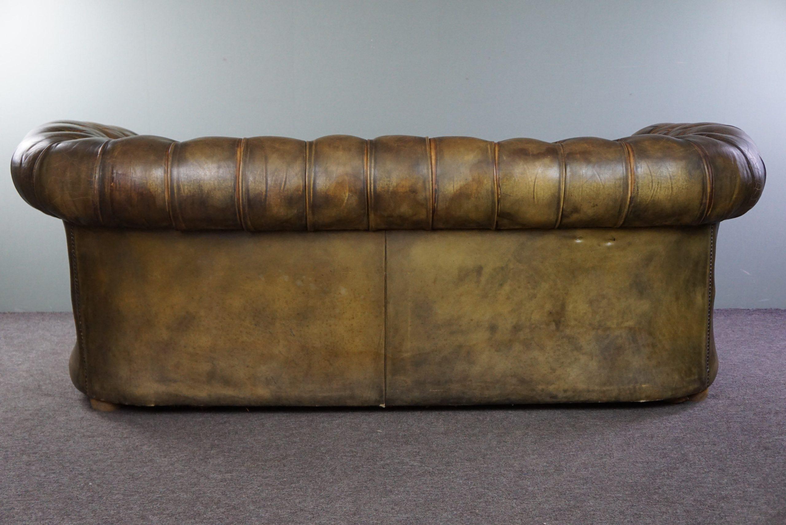 Offered is this super sturdy 2.5-seater chesterfield sofa in a beautiful moss green color. This gorgeous sofa in its beautiful green color is a feast for the eyes. It has acquired some scars over its already quite long life, but in our opinion, that