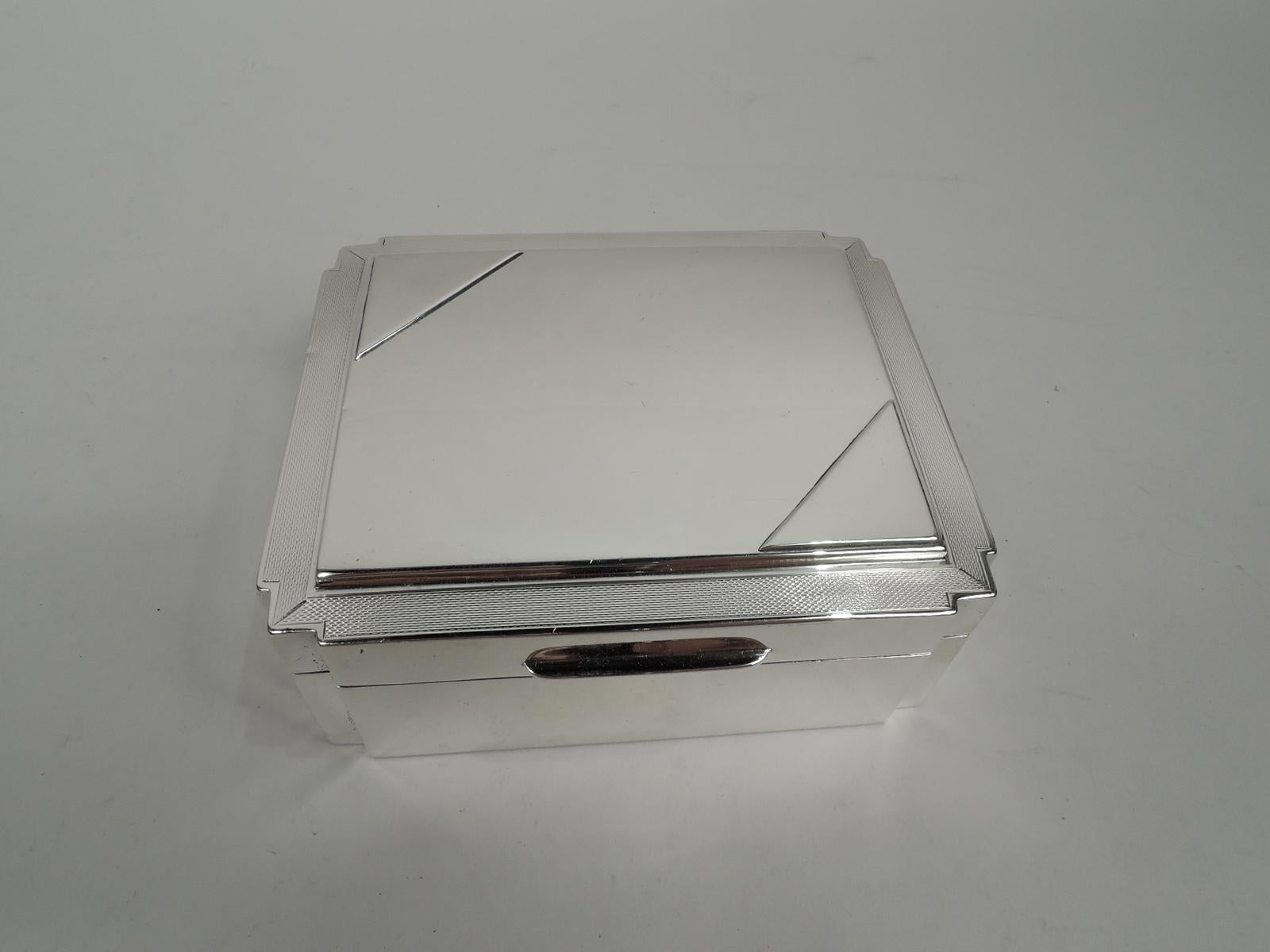Super stylish Art Deco sterling silver box. Made by Mappin & Webb in Birmingham in 1930. Rectangular window with straight plain sides and unusual angular corners. Cover hinged and tabbed with engine-turned ornament bordering plain and raised top