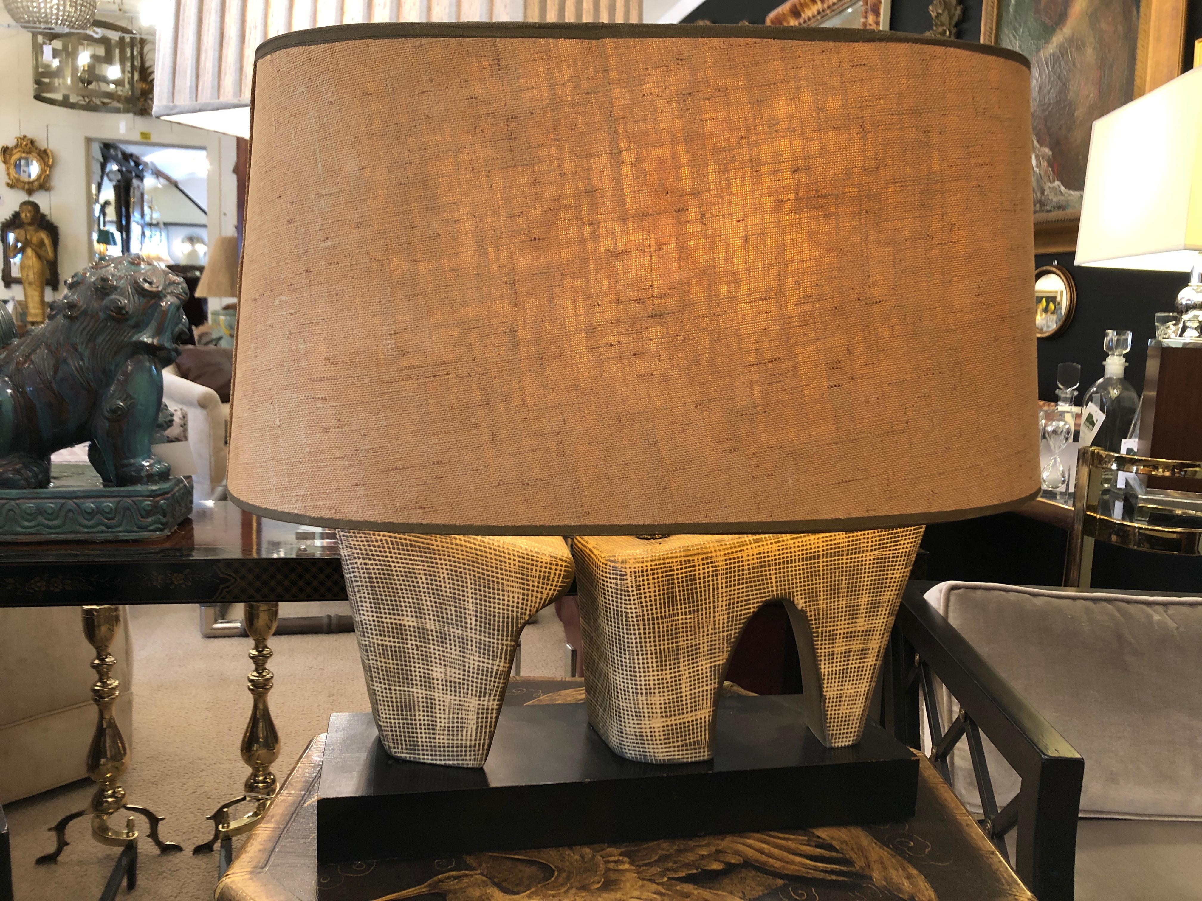 A super cool Mid-Century Modern lamp having a neutral colored sculptural textured pottery base of two abstract shapes on a black wooden slab and topped off with a fabulous large original oval linen shade.
Base is 16 x 5.
 