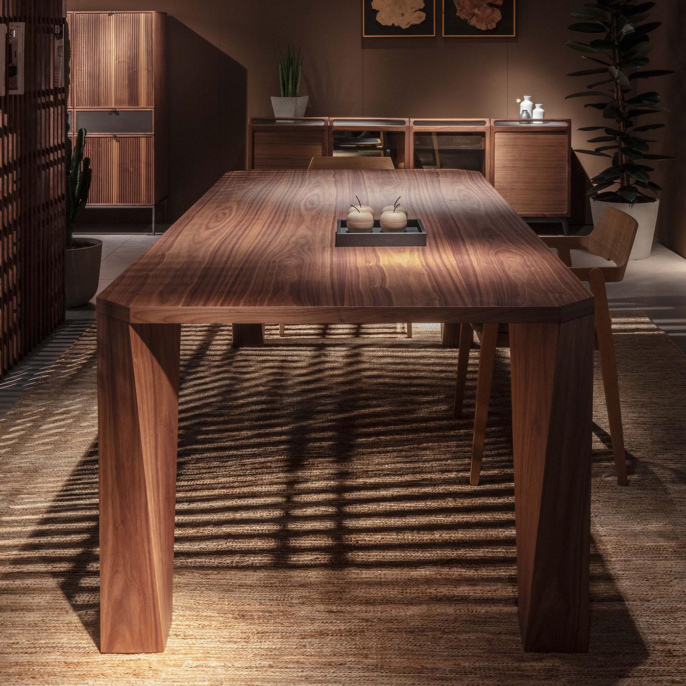 Distinguished by its walnut wood structure, this rectangular table is defined by four solid wood legs that captivate with their unique silhouette. Each leg showcases intricate craftsmanship, creating a dynamic torsional movement. The table