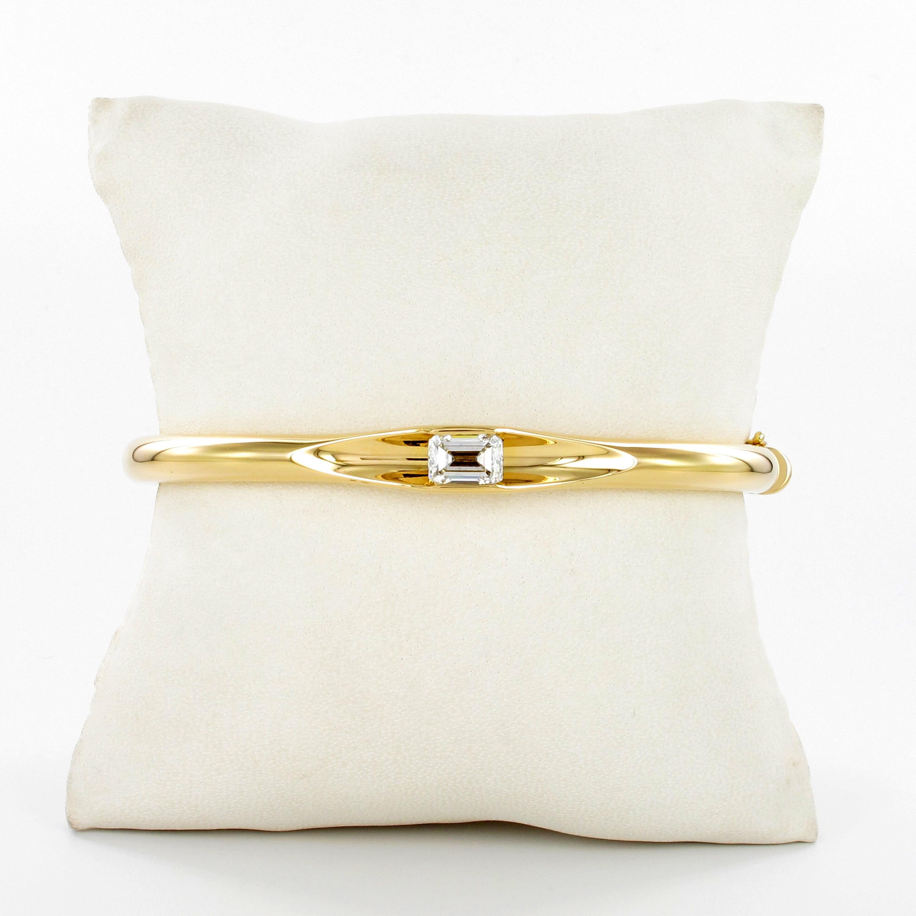 This incredibly sleek and chic bangle in 18 karat yellow gold by Swiss jeweller Gübelin is set with a 1.34 carat emerald-cut diamond of F/G colour and si2 clarity. 
Understated and dazzling at the same time, this bangle can be worn day and