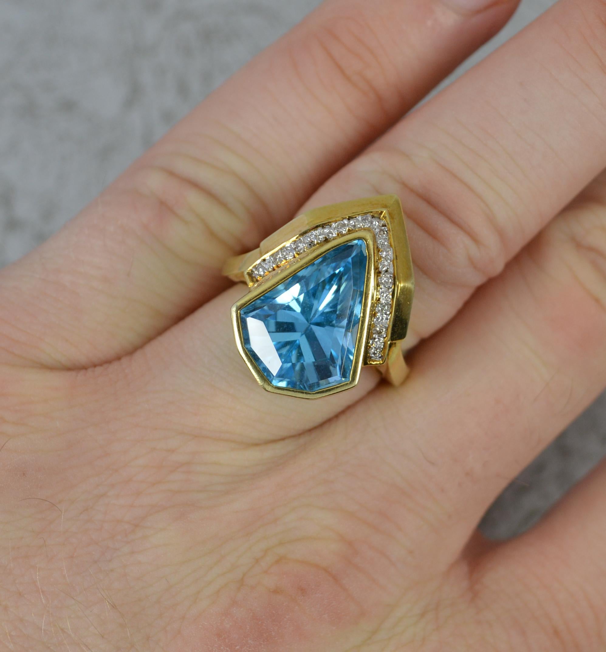 A beautiful Topaz and Diamond statement ring.
Solid 14 carat yellow gold example.
Designed with an unsually cut vivid blue topaz with many round cut diamonds set above.
12mm x 16mm stone. 
17mm x 23mm geometric head. Protruding 9mm off the finger.