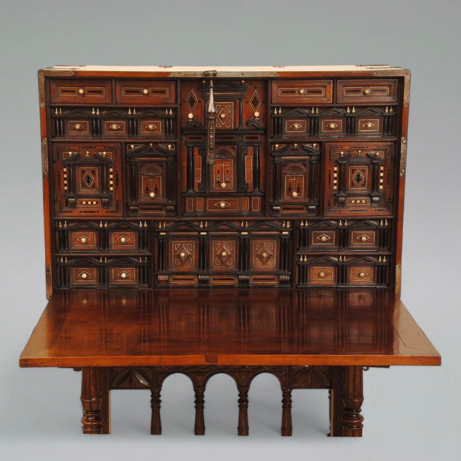 Un buen ejemplo de vargueno español de finales del siglo XVII sobre peana. Este primitivo mueble de caoba tiene las monturas de hierro originales y el frente de caída se abre para revelar un interior bellamente ajustado con diseño arquitectónico en