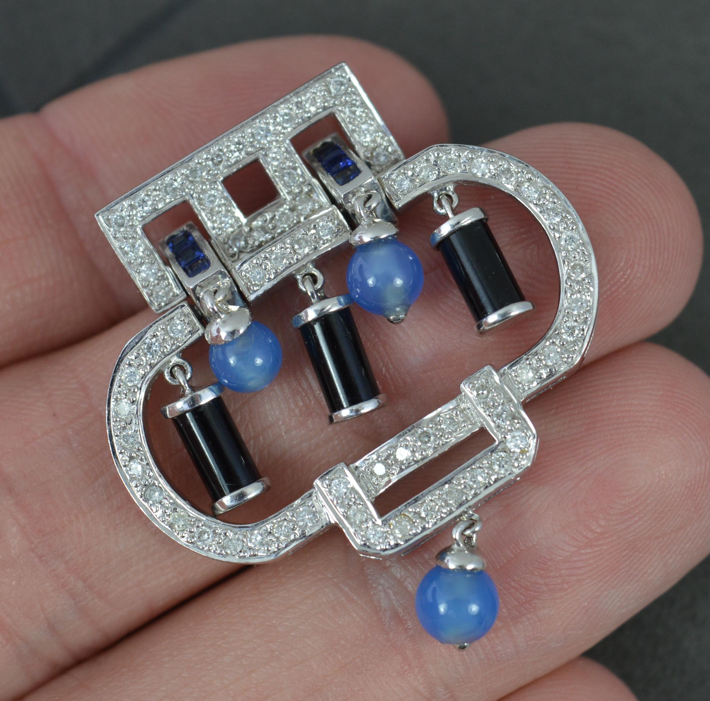 A stunning contemporary pendant.
Solid 18 carat white gold example.
Designed with many round brilliant cut diamonds encrusted into the piece throughout, approx 0.75cts. Set with an additional six princess cut blue sapphires. To the centre are five