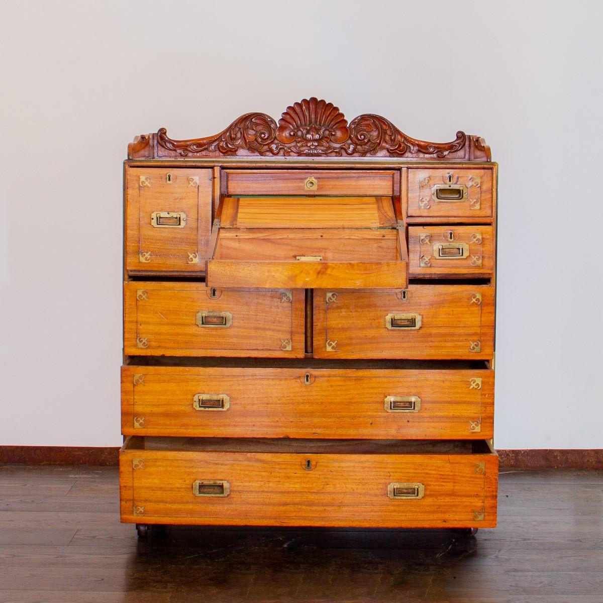 A late 19th century camphor wood campaign secretaire chest with decorative brass inlay bordering each drawer with fleur-de-lys style corners. The top section has a central drawer over two deep drawers and is flanked by one large drawer and two