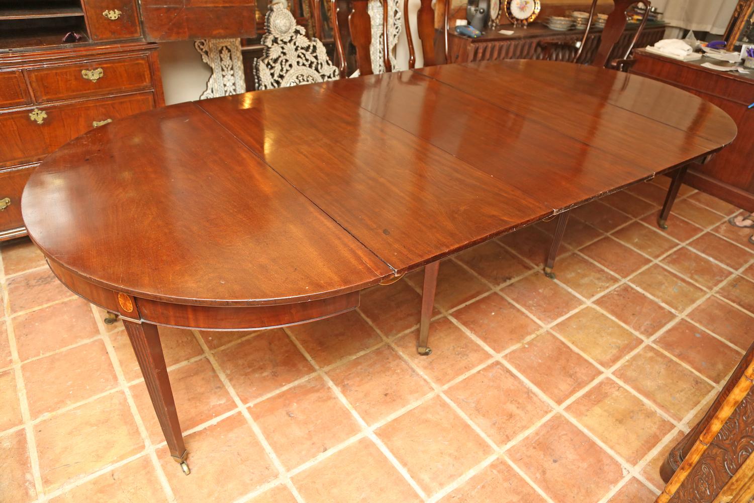 This is a superb quality solid mahogany antique English dining table with 3 leafs also having a pair of D end console tables. Very good quality very heavy with the original patina. It sits on square tapered legs with brass cup castors to the base