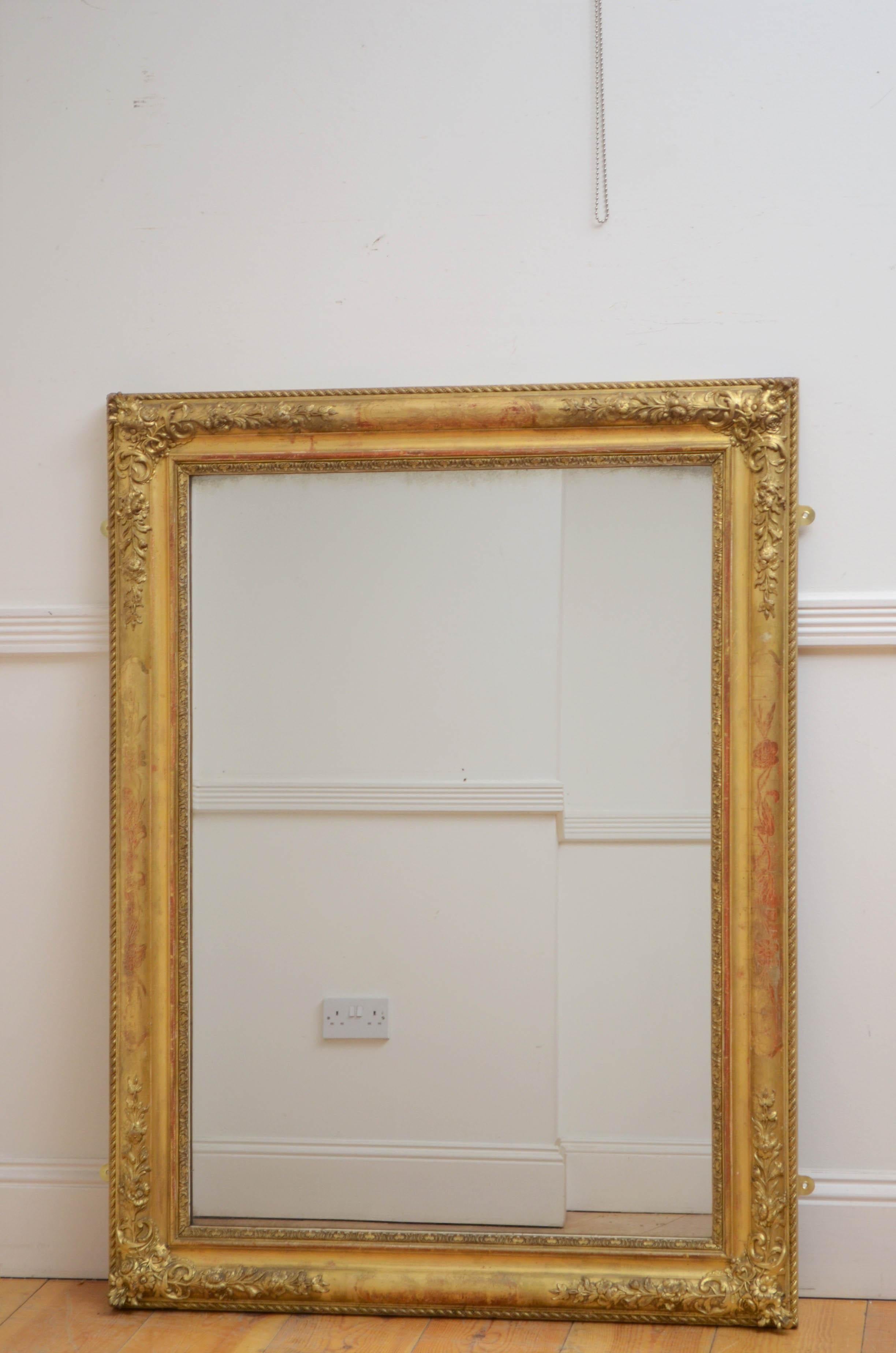 0227 Outstanding French gilded wall mirror, having original glass with air bubbles and minor silvering in moulded giltwood frame with flowery corners and leaf scrolls engravings. This antique mirror retains its original glass, original gilt and