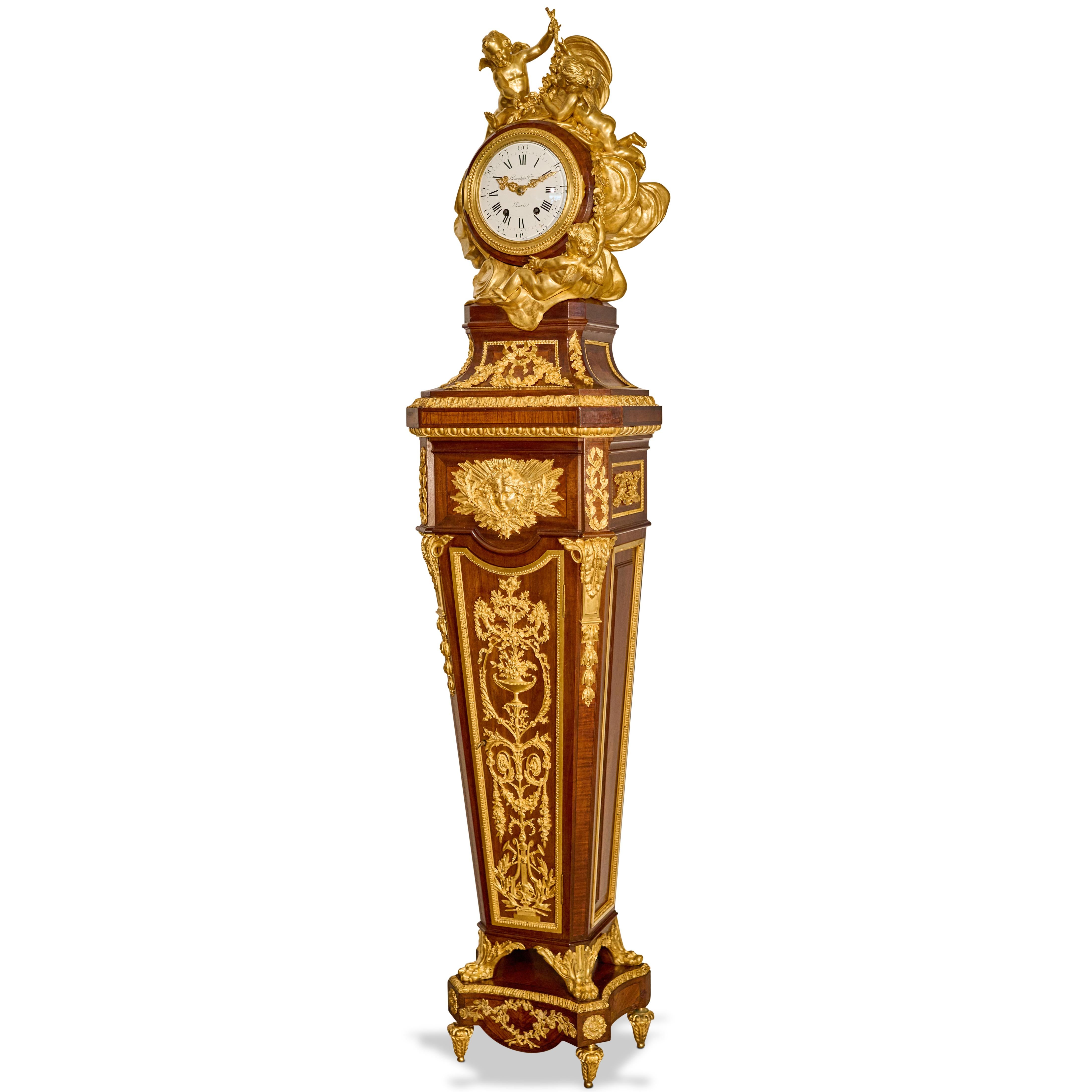 Orologio a pendolo a cassa lunga di Haentges Freres, in stile Luigi XV francese, di superba qualità, con montatura in mogano e intarsio di Re-Wood. 
La cassa del tamburo è montata con putti giocosi con ghirlande di fiori in mezzo a nuvole