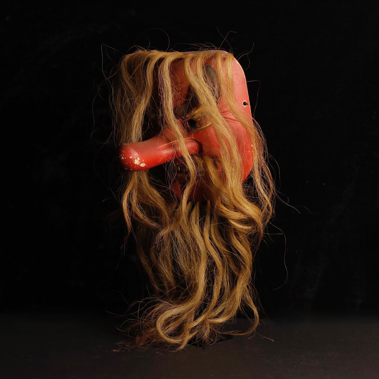 Un masque Tengu antique remarquable représentant le puissant esprit des montagnes du folklore japonais.
Sculpté dans du bois et recouvert d'une laque noire, le masque présente des détails en crin de cheval et une expression dramatique typique de