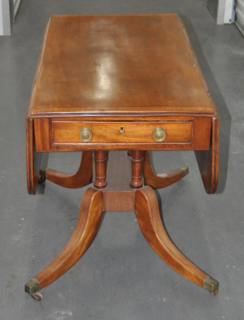 Superb 19th century mahogany English Regency breakfast table, circa 1815.

Drop-leaf table on a pedestal base w/ one end drawer, one faux drawer and brass capped feet.

Dimensions: 41
