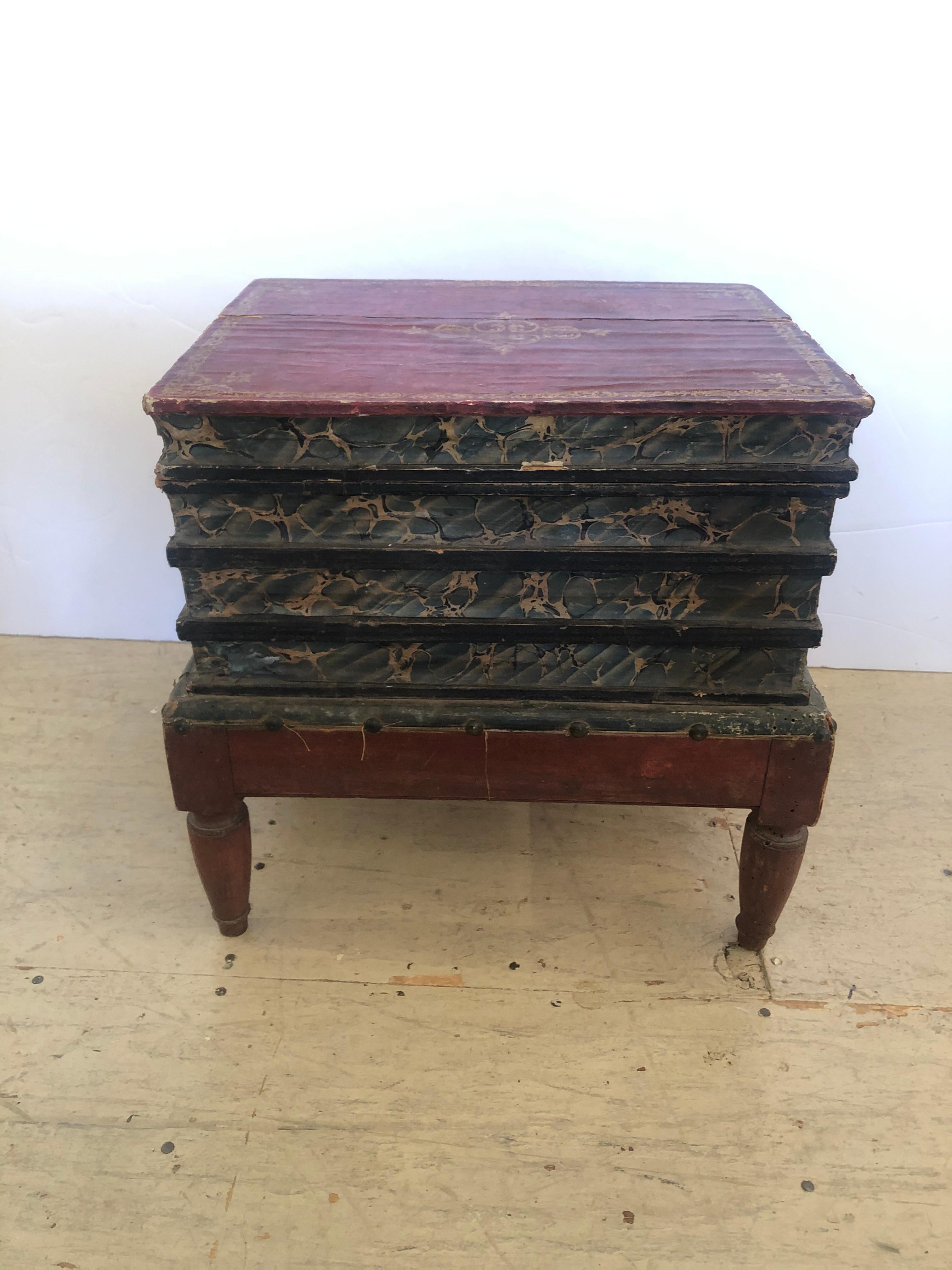 A rare character rich 19th century jewel of a side table and decorative box in the shape of stacked books on stand, having original Italian wrapped paper on wood, and lid that opens to reveal storage and cubby inside. Intentionally left in