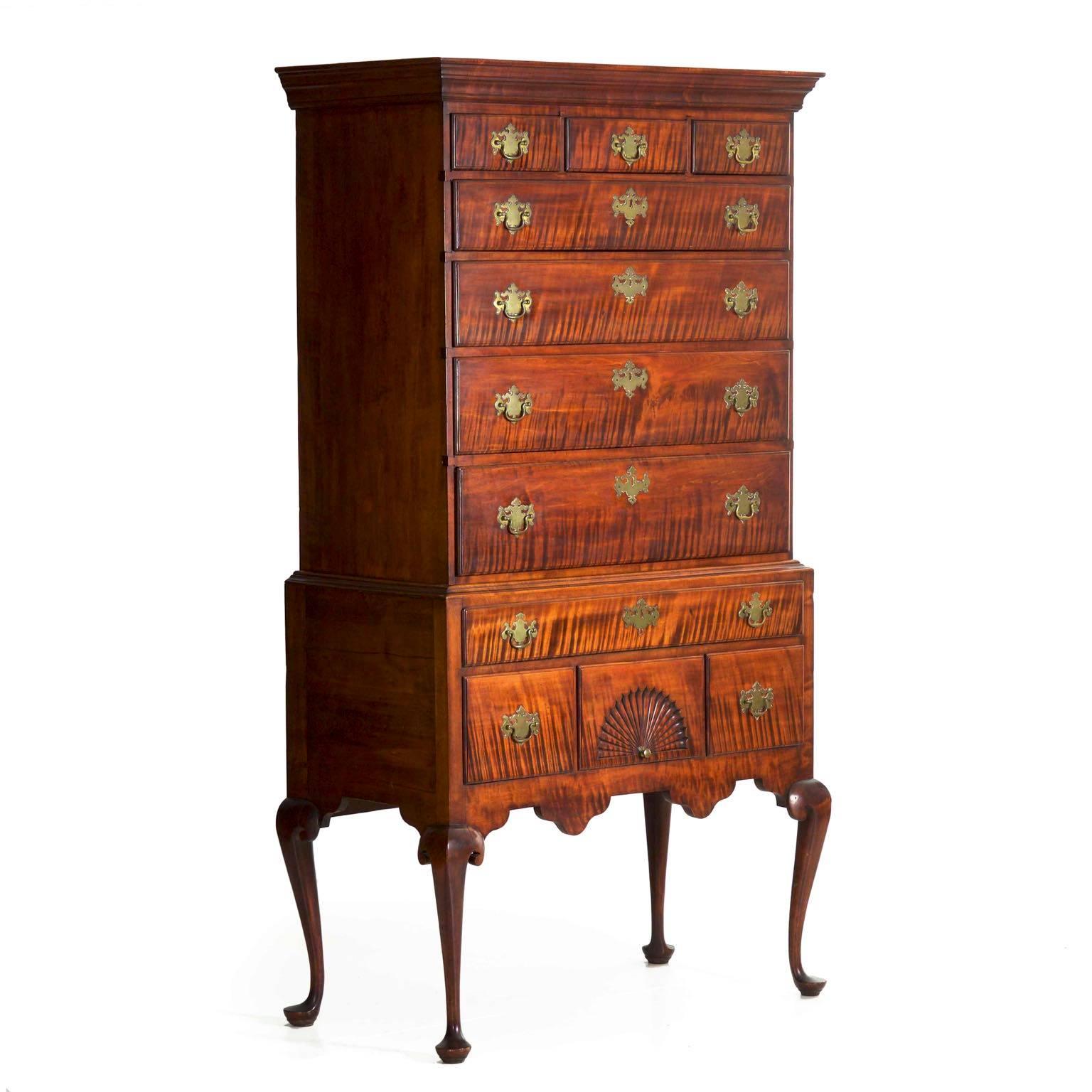 This superb New England highboy is crafted out of a powerful curly maple hardwood which lends gorgeous grain striations across the graduated drawers. There is always an interesting progression in the furniture design that ranges from the utilitarian