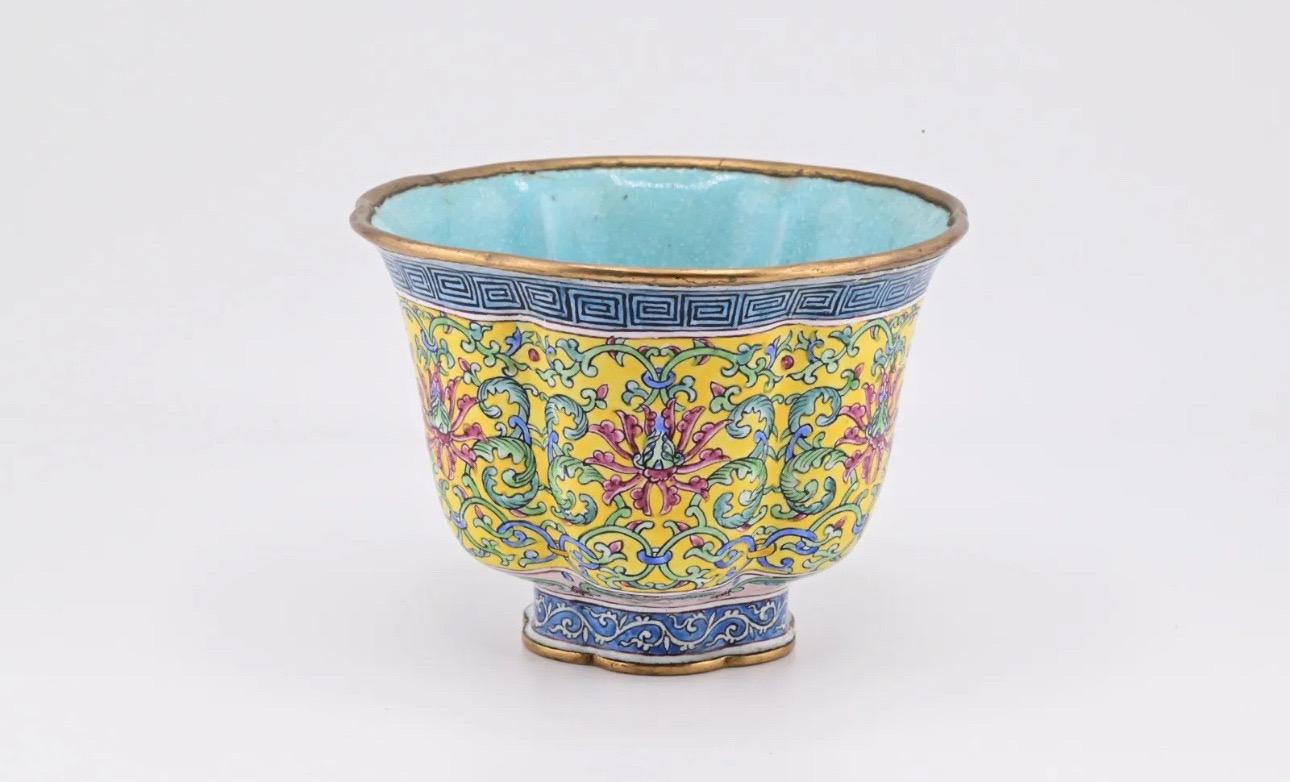 This is a beautiful antique Chinese enamel Canton cup that features a stunning yellow ground with intricate designs. The cup is made of cloisonne, a primary material that adds to its exceptional quality. Its four-character mark indicates its age,