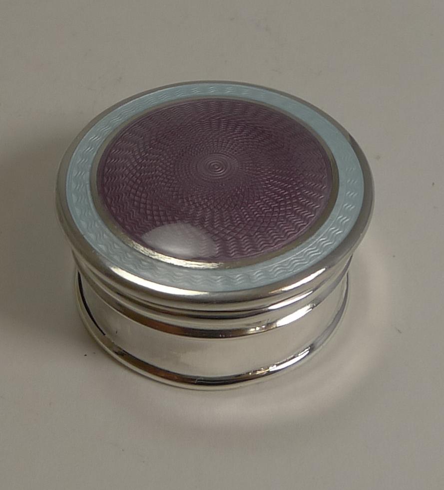 A fabulous little pill box made from English sterling silver with a hinged lid and gilded interior.

The top of course is what makes this a special and highly sought-after example decorated with a central lilac coloured guilloche enamel and a band