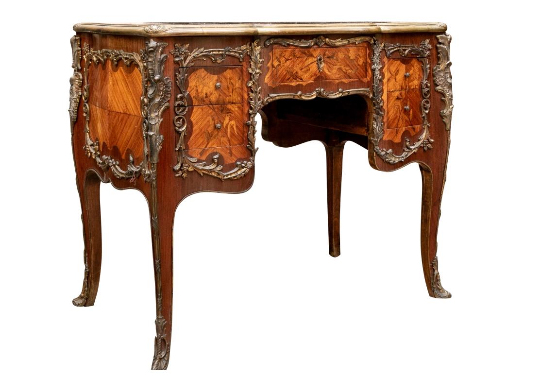 Cette belle table d'écriture française, à la fois audacieuse et discrète, se distingue par la qualité de son exécution. Le plateau à trois sections ainsi que tous les tiroirs et les panneaux arrière présentent des branches et des fleurs délicatement