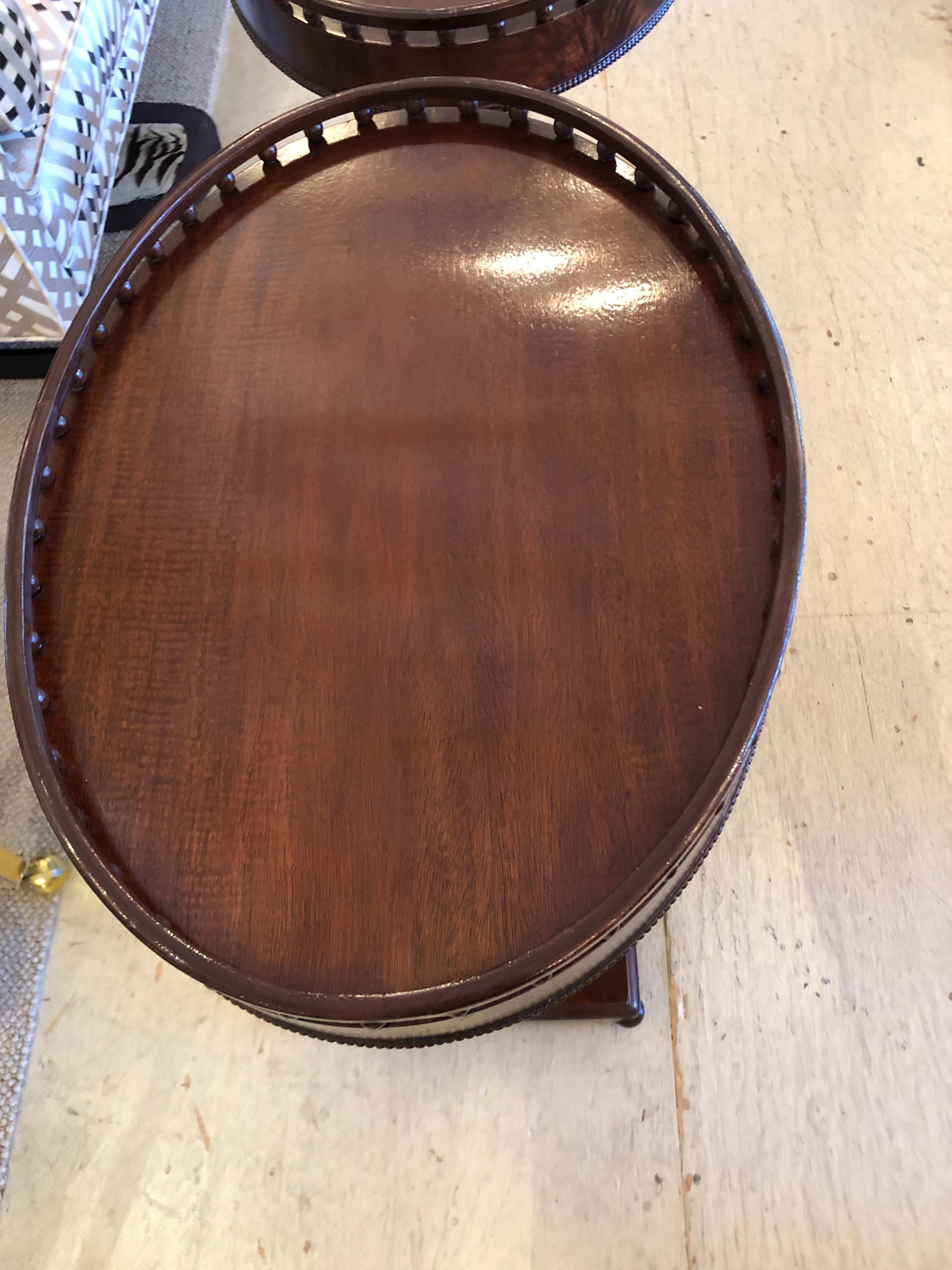 A gorgeous pair of antique neoclassical mahogany oval side tables having lyrical lyre bases, wooden galleries around the tops and ball feet.