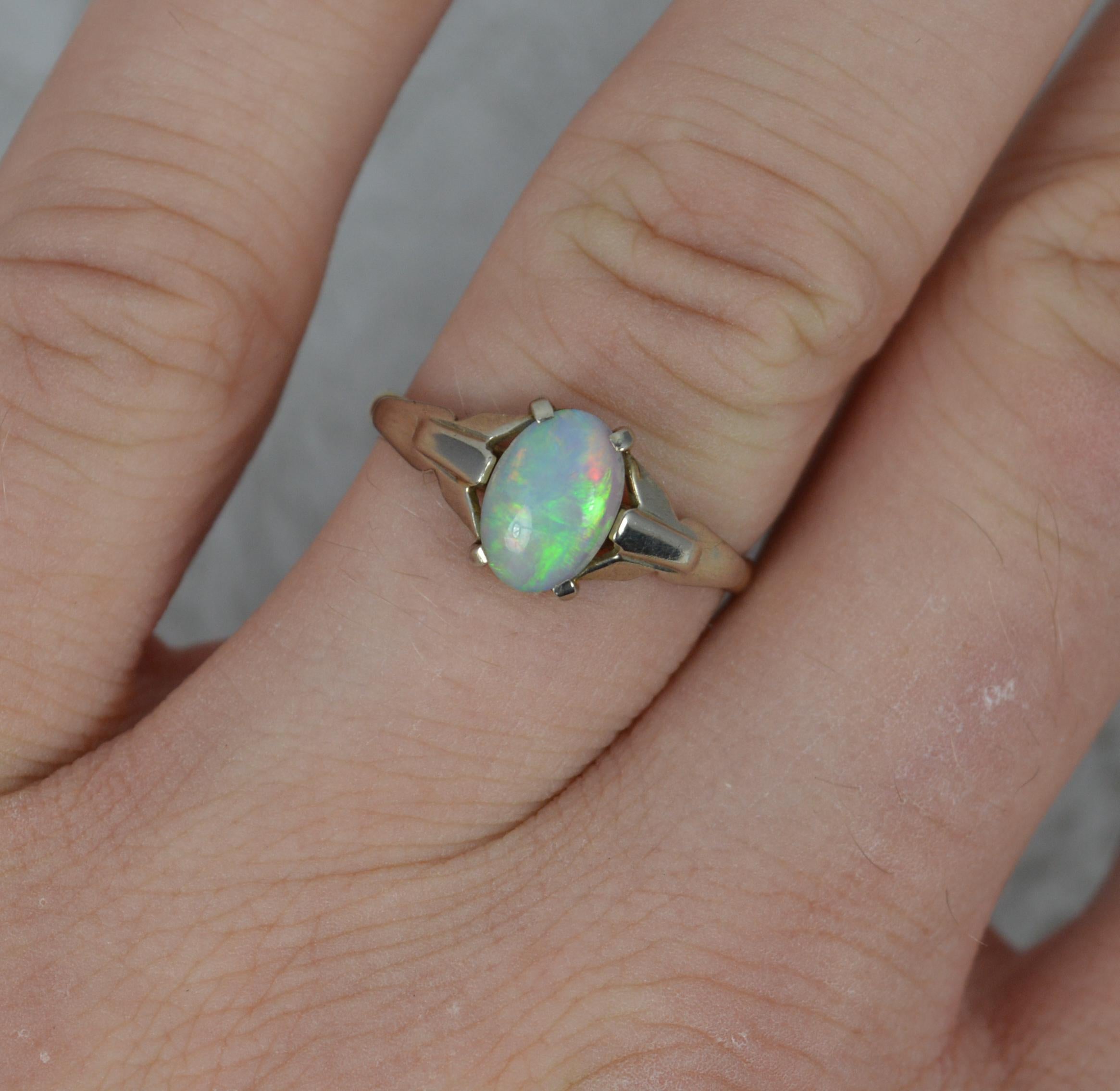 An art deco ring.
Solid 9 carat gold example.
Natural opal, flashes of all colours.

Size O 1/2 UK, 7 1/2 US. Sizeable. 1.7 Grams. 5.7mm x 8.2mm approx. Set into a fine white gold or platinum setting. 

Very good for age. Clean, solid band, issue