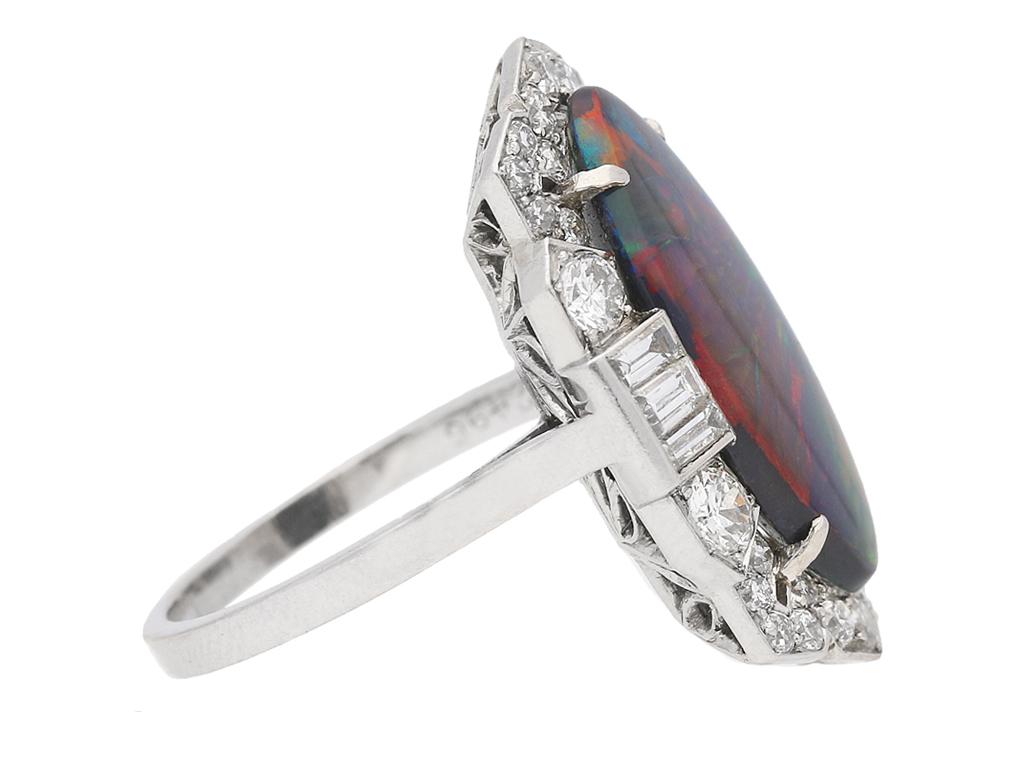 Art Deco black opal and diamond ring. Set with a marquise shaped cabochon natural unenhanced black opal in an open back claw setting with an approximate weight of 3.53 carats, encompassed by thirty round old cut diamonds in open back grain settings