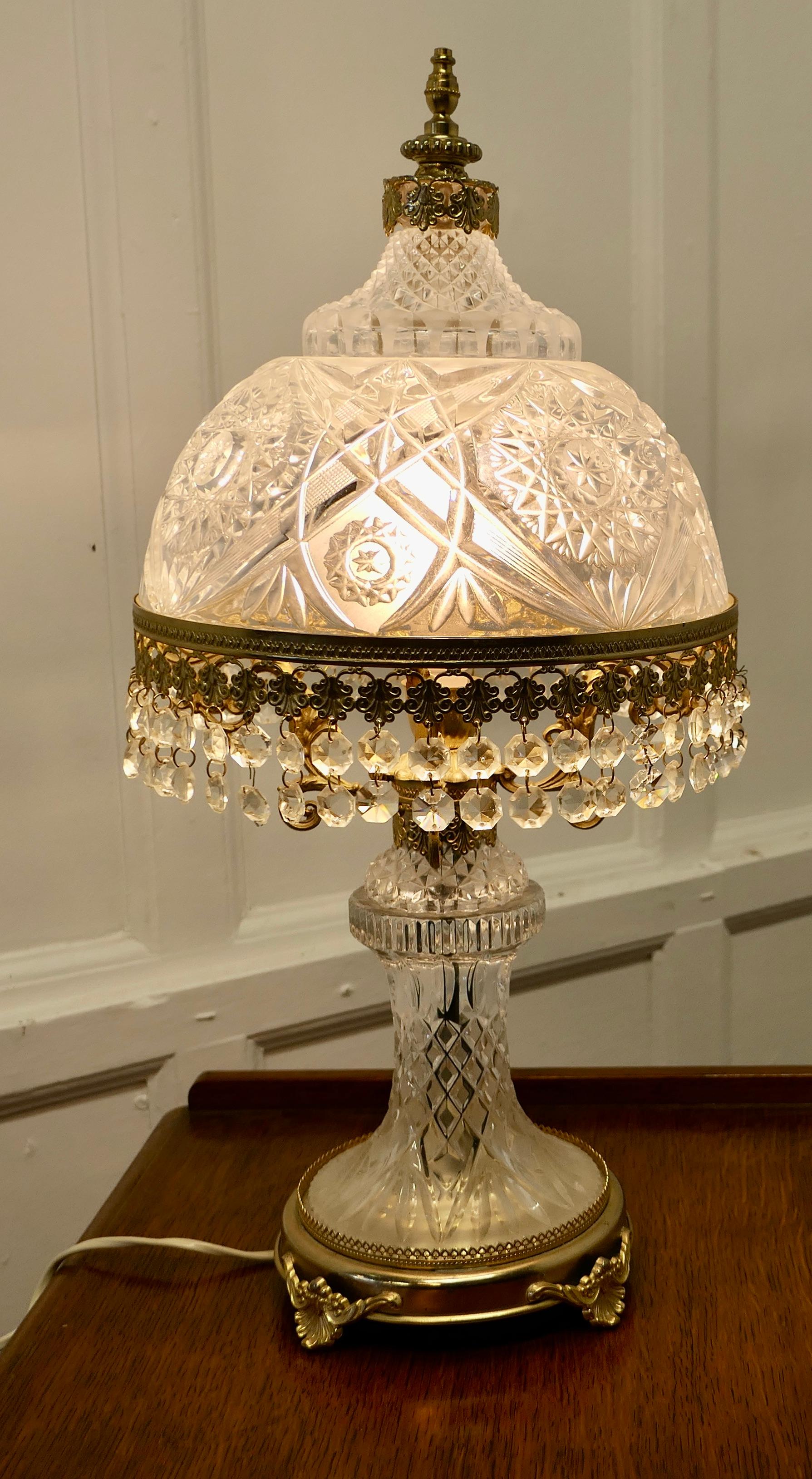 Superb Art Deco Glass Lamp and Glass Shade

This is a very pretty piece, the base of the lamp has around shape set on brass feet, both the base and the lamp are made in glass and set with brass mounts and cut glass beads 
All the wiring is new,