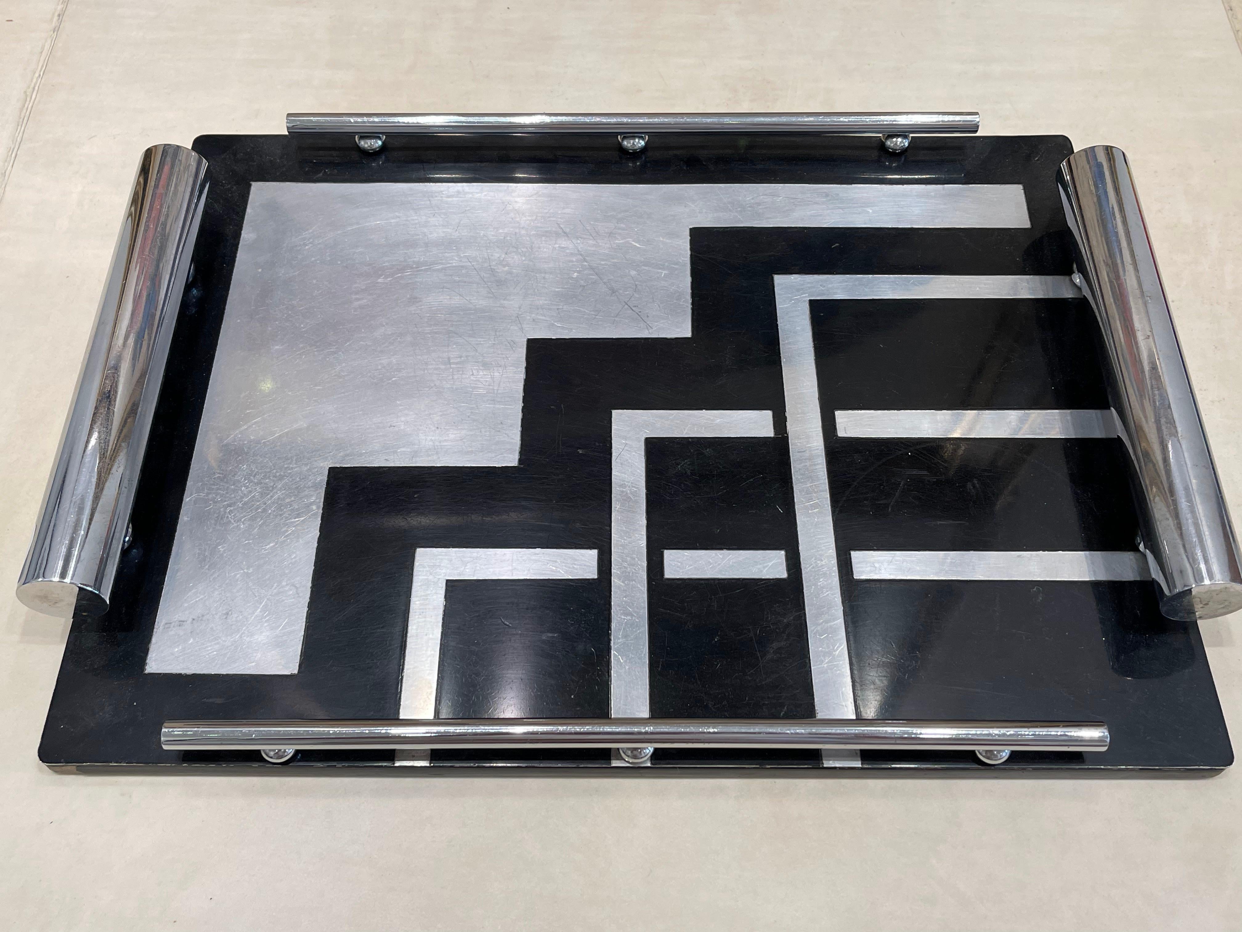 This rectangular tray adorned with geometric patterns in typical  Bauhaus style. The pattern is asymmetrical with regular motifs, the lines are clean and simples. This tray dates back to the 1930s.

The tray is made of black lacquered  wood, inlaid