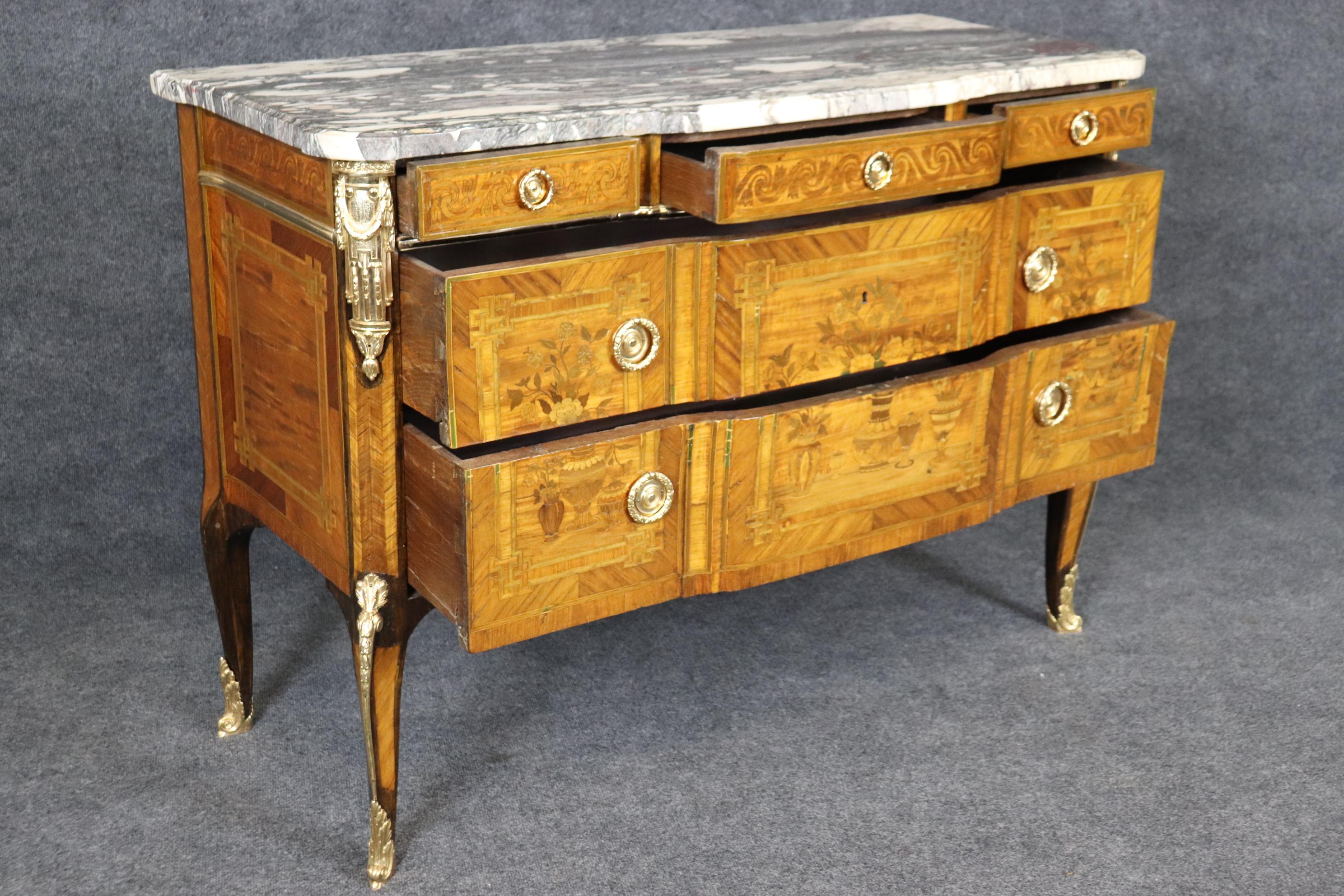 This is a spectacular and brightly polished bronze and brass ormolu adorned commode in the French Louis XV style. The piece has inlai and is in good antique condition with minor signs of use and age. The marble top is stunning and has a great